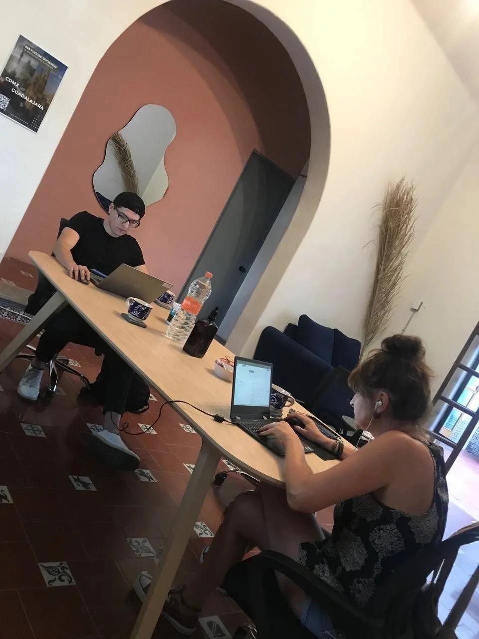 Two people working on laptops at the coworking table in the coliving space