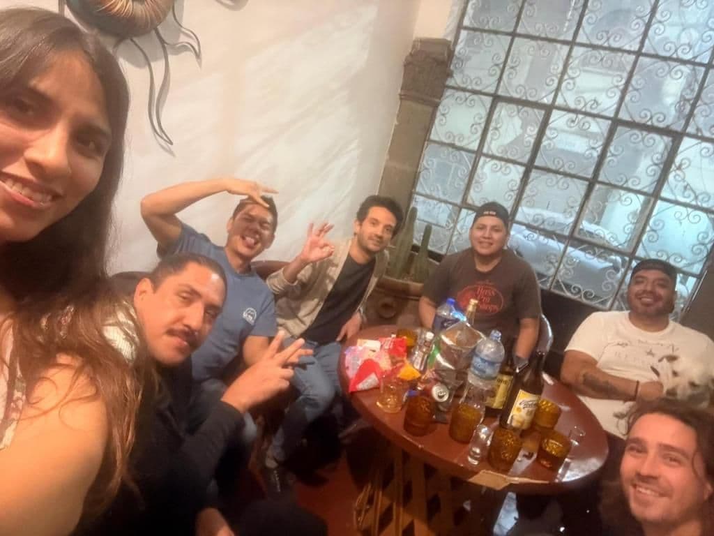 Group of coliving residents socializing indoors around a table with drinks