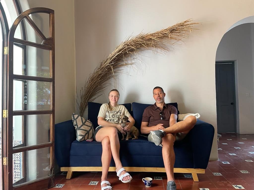 Two people sitting on the blue sofa in the living lounge with a dog