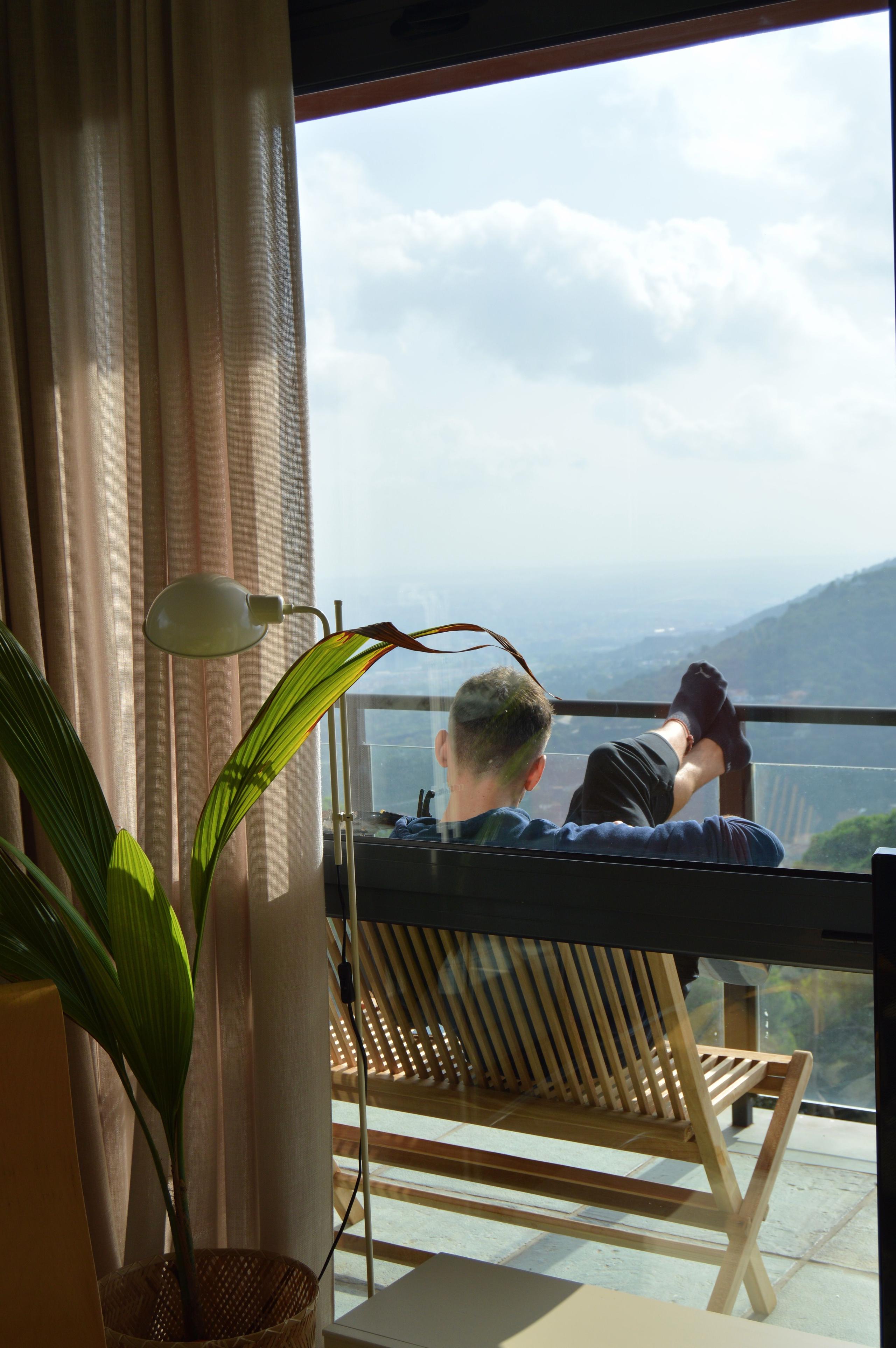 A person relaxing on a terrace chair, looking out at the mountain and valley views.