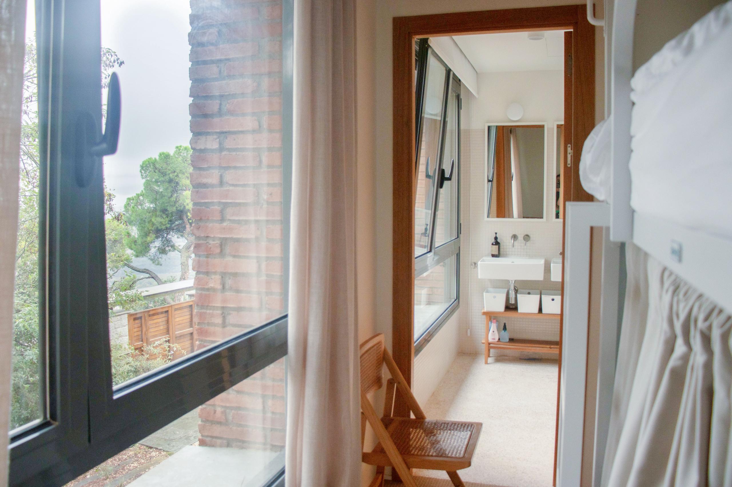 Shared suite room with bunk beds, a window with garden view, and a view into the shared bathroom.