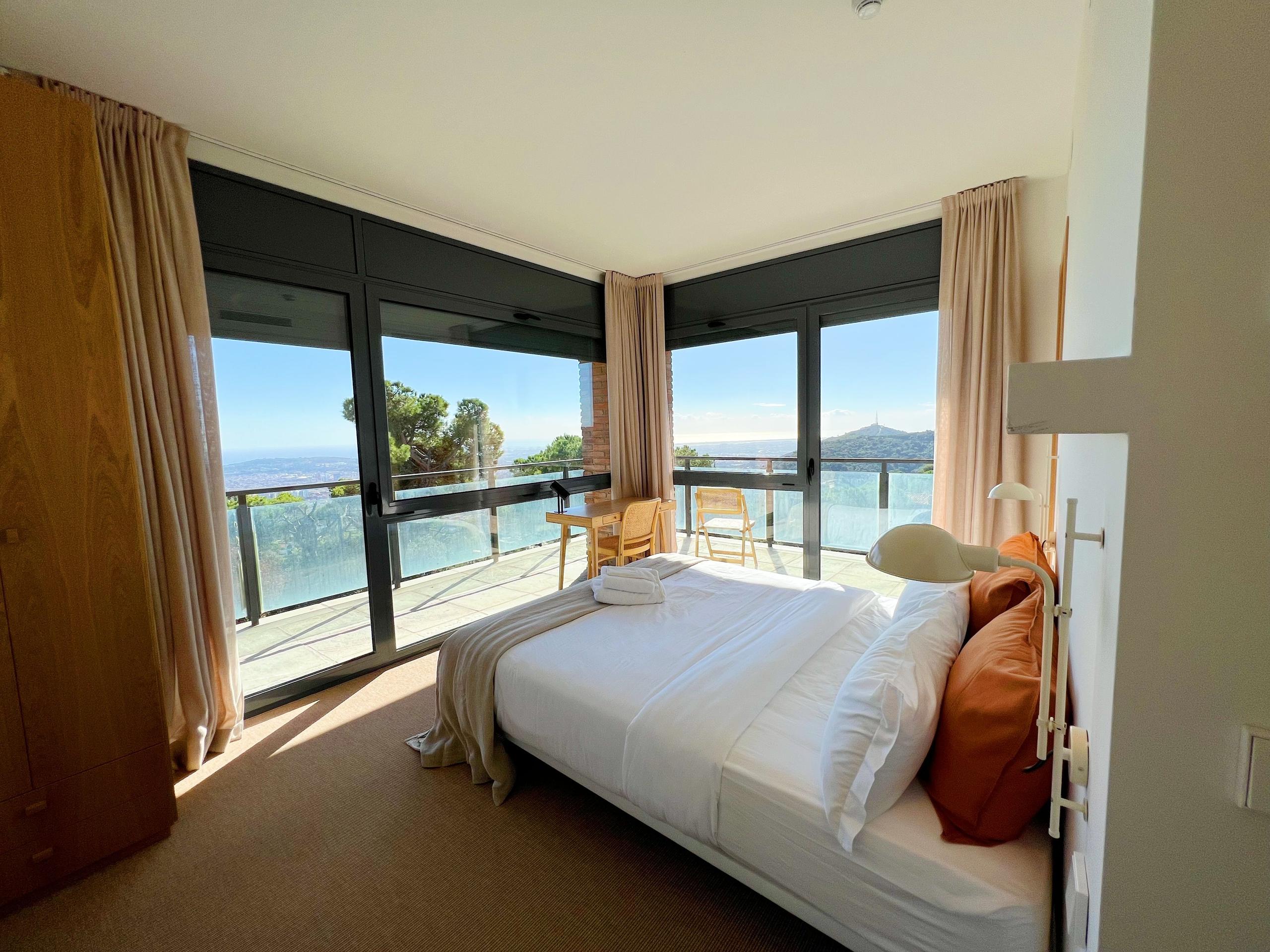 King studio room with large floor-to-ceiling windows and a private terrace overlooking the sea and city.