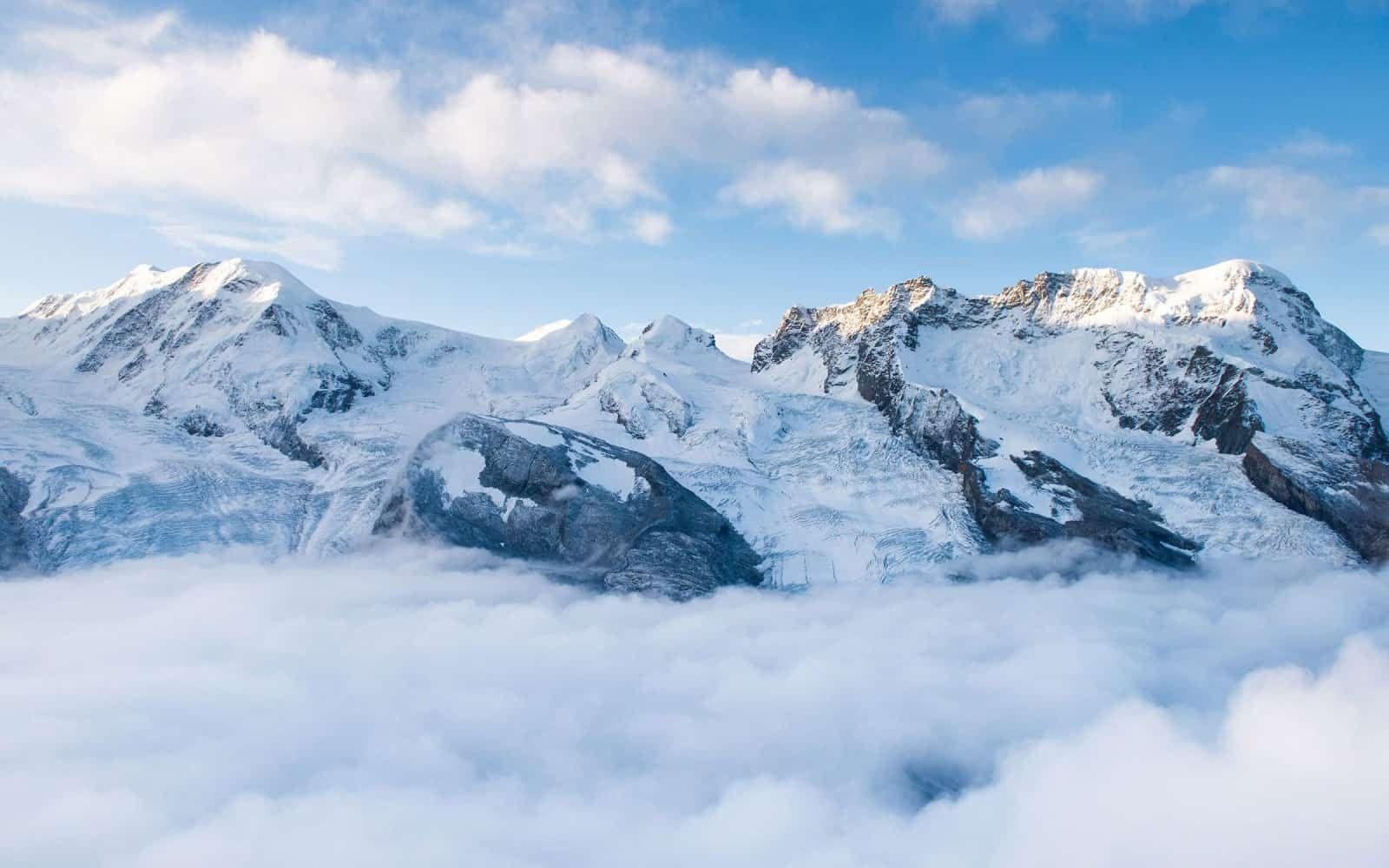 Snow-capped mountain peaks rising above clouds in the French Alps