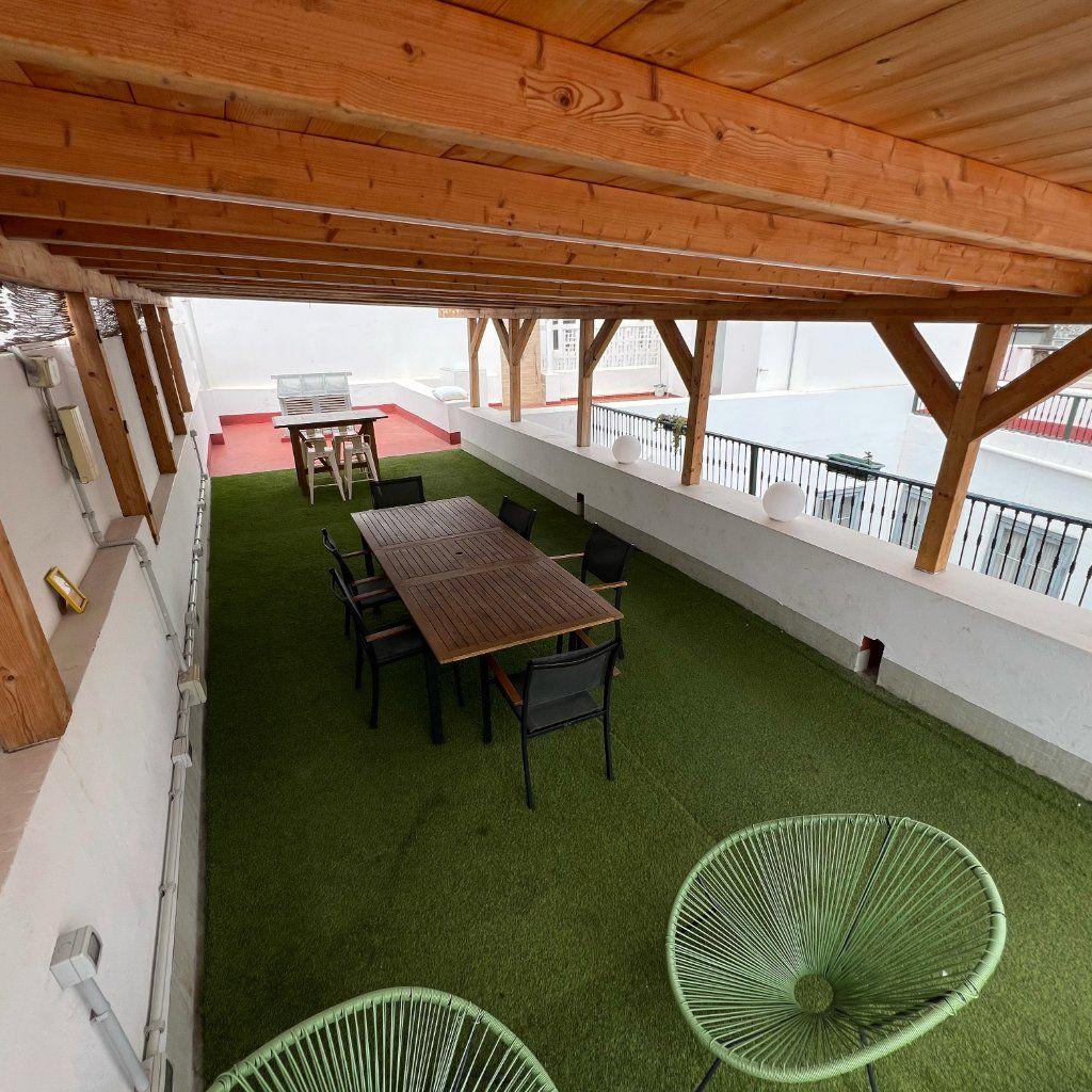 Roof terrace with covered area for working, eating or hanging out, with tables for 10 people and sun loungers