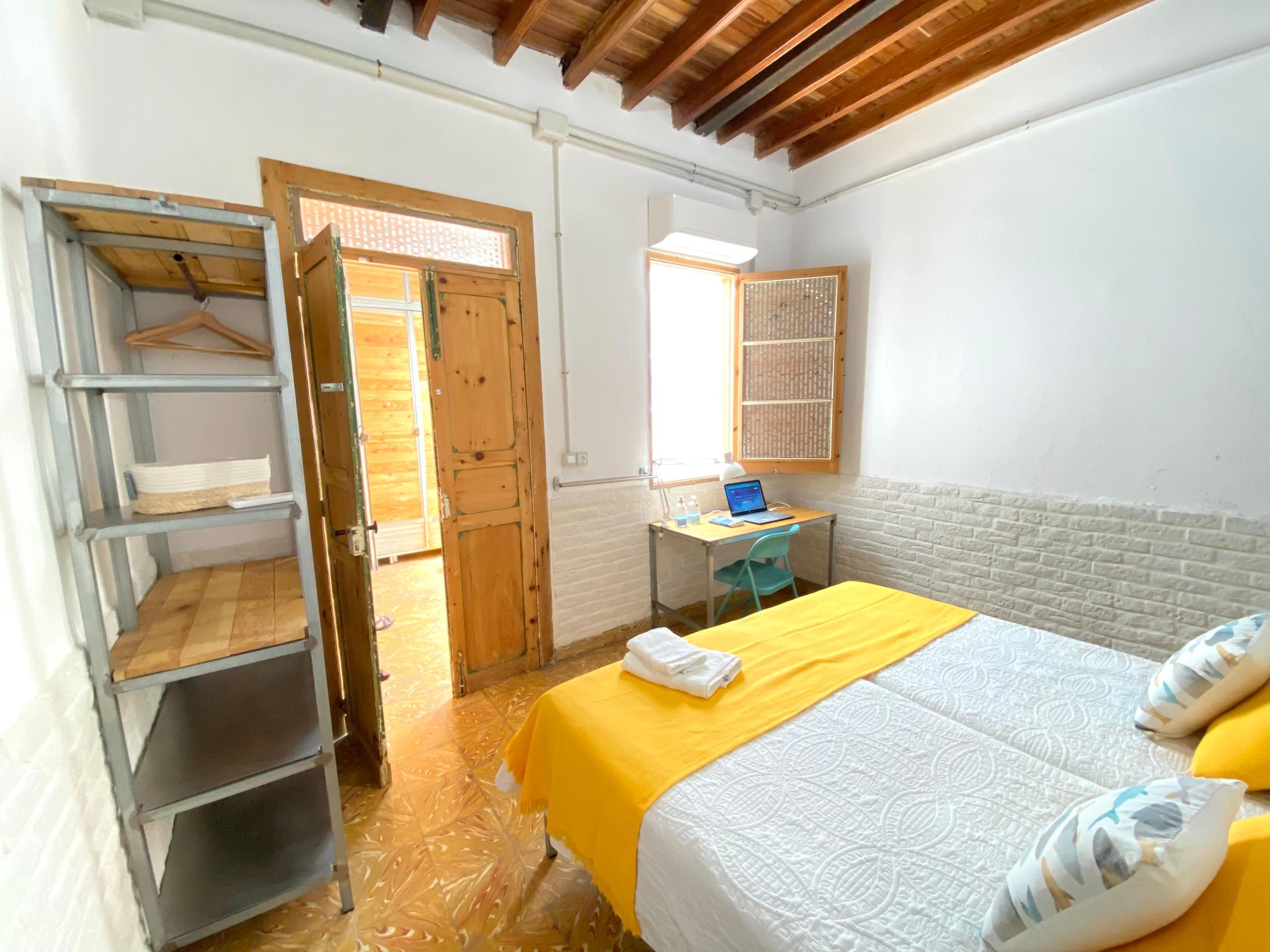 Double room with two beds in a coliving space in Gran Canaria, ideal for remote workers. The room includes a desk and a wardrobe.