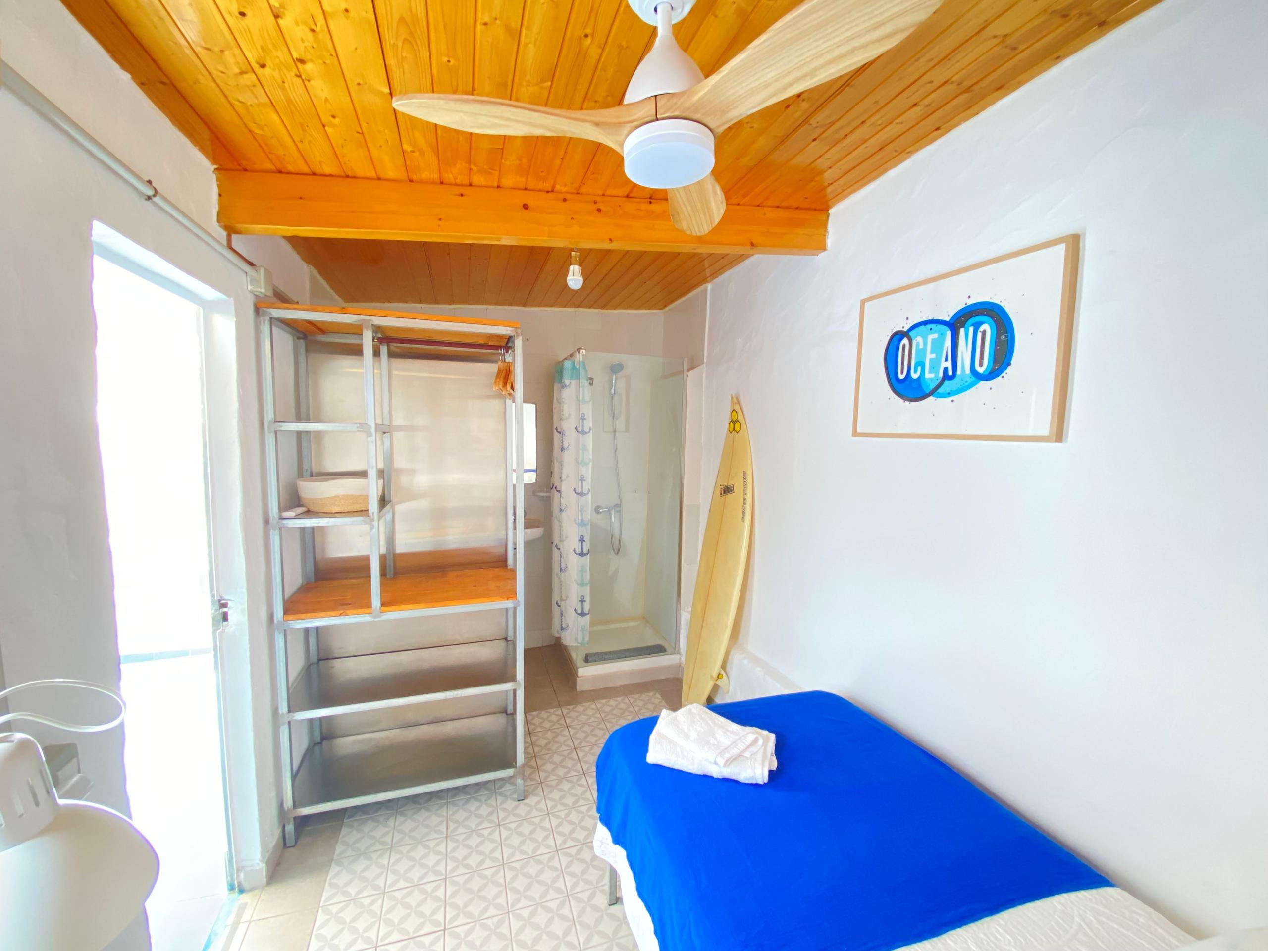 Ideal comfortable ensuite single room in a Coliving in Gran Canaria, with bed, desk, ceiling fan, and toilet inside of the room. Next to the terrace, with plenty of sunlight