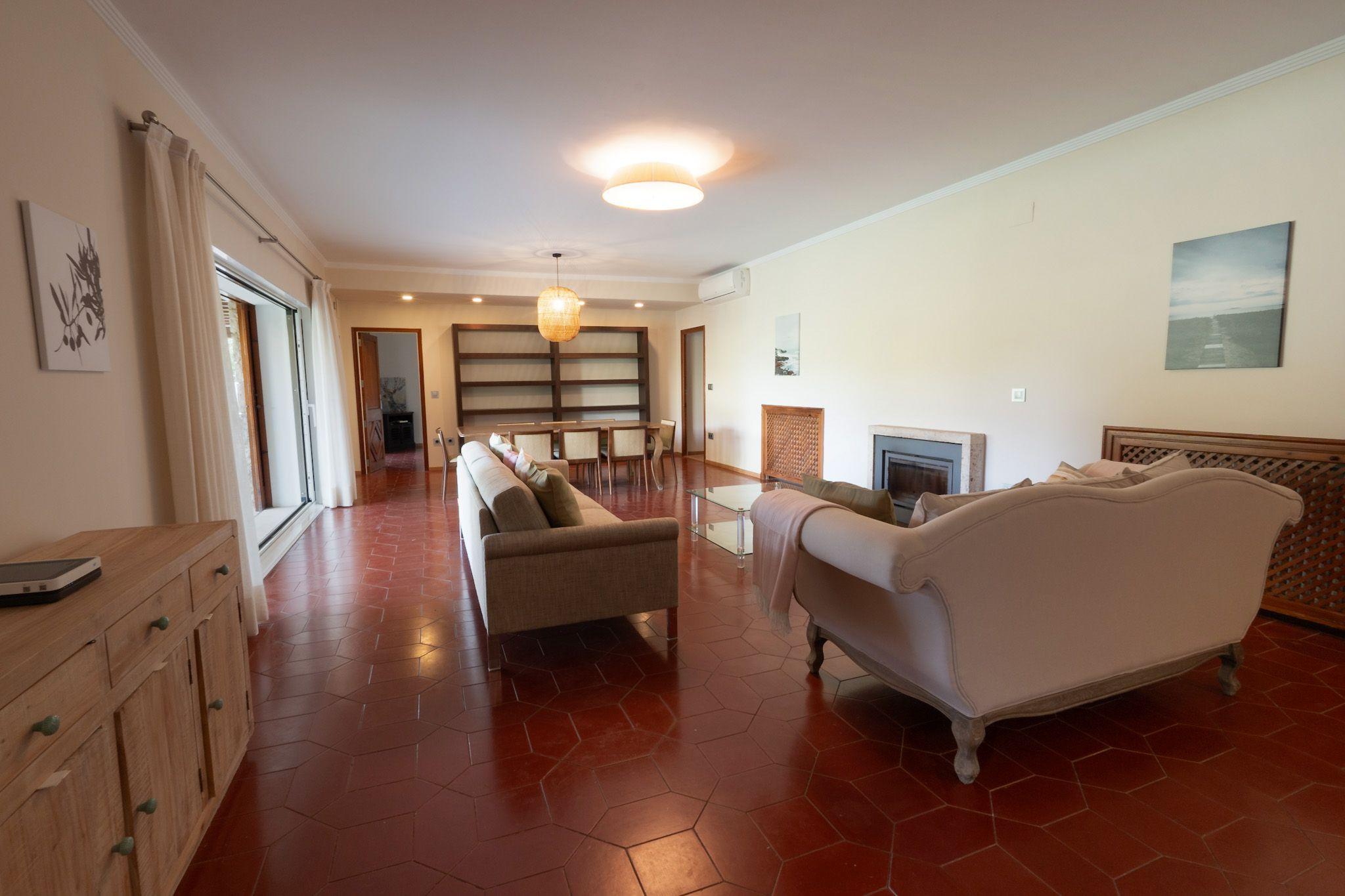 Spacious living room with sofas, fireplace, bookshelves and garden access