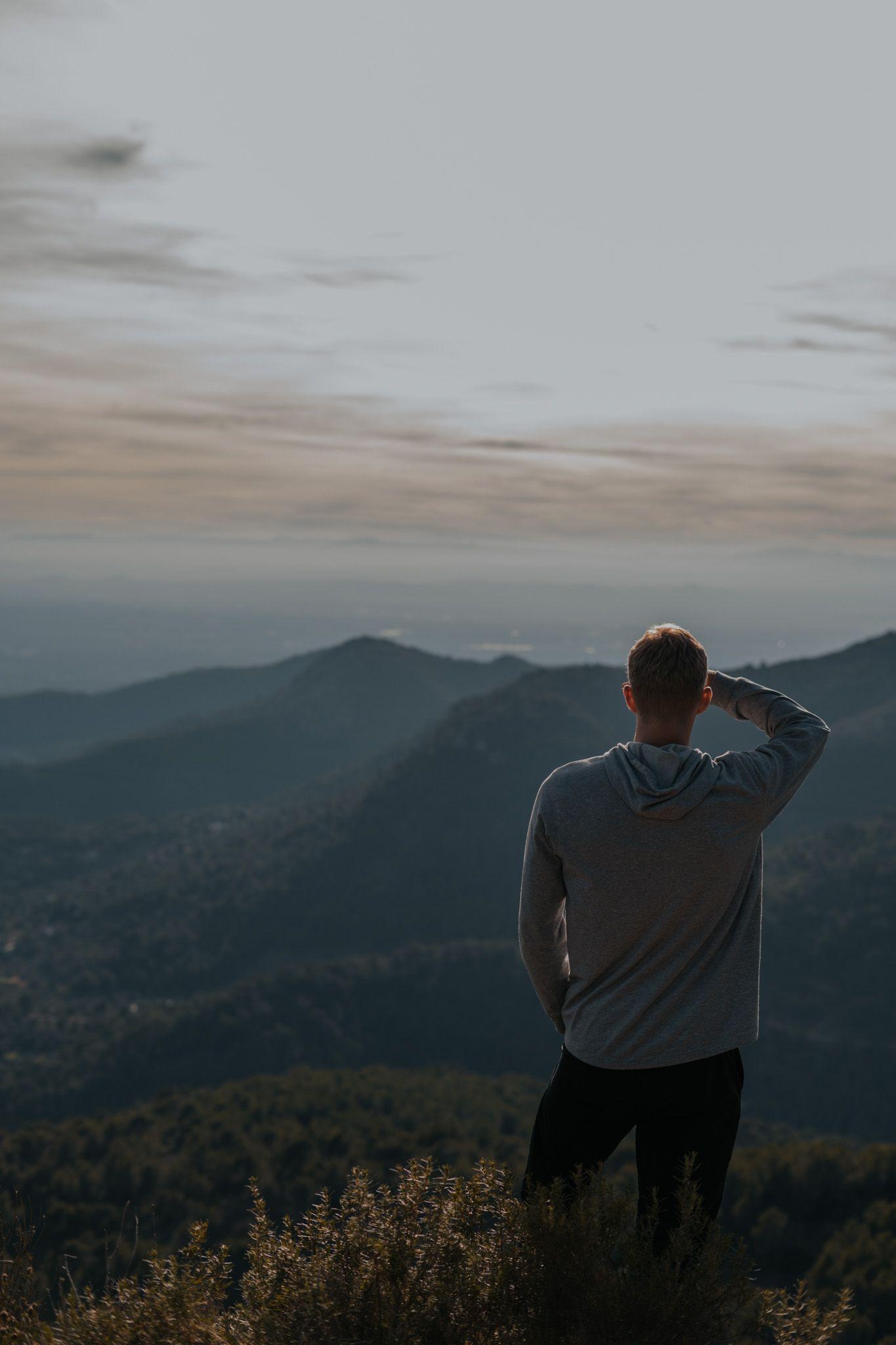 Person standing on a hilltop overlooking a mountain landscape near Valencia