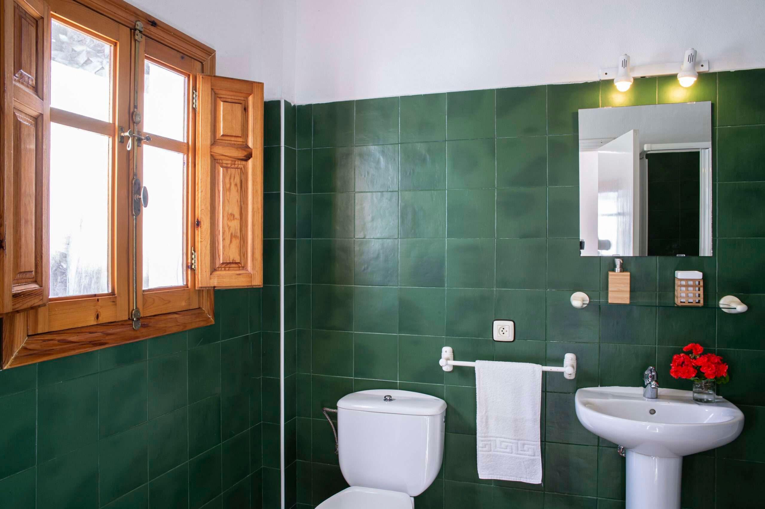 a bathroom with green tiles and a window