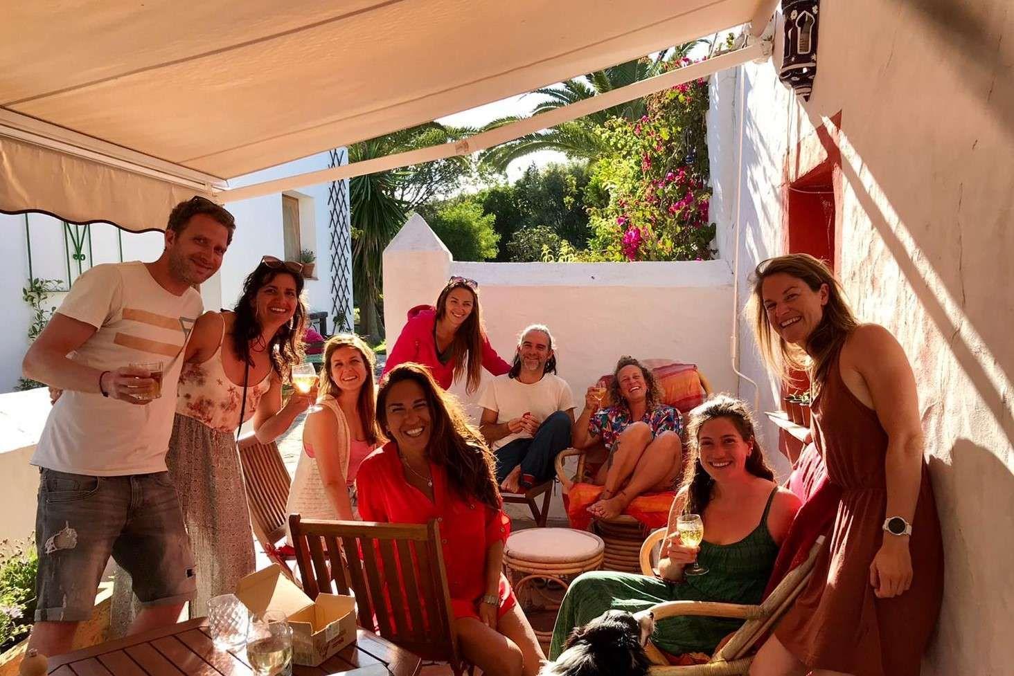 group of people sitting on a terrace, smiling and having a drink