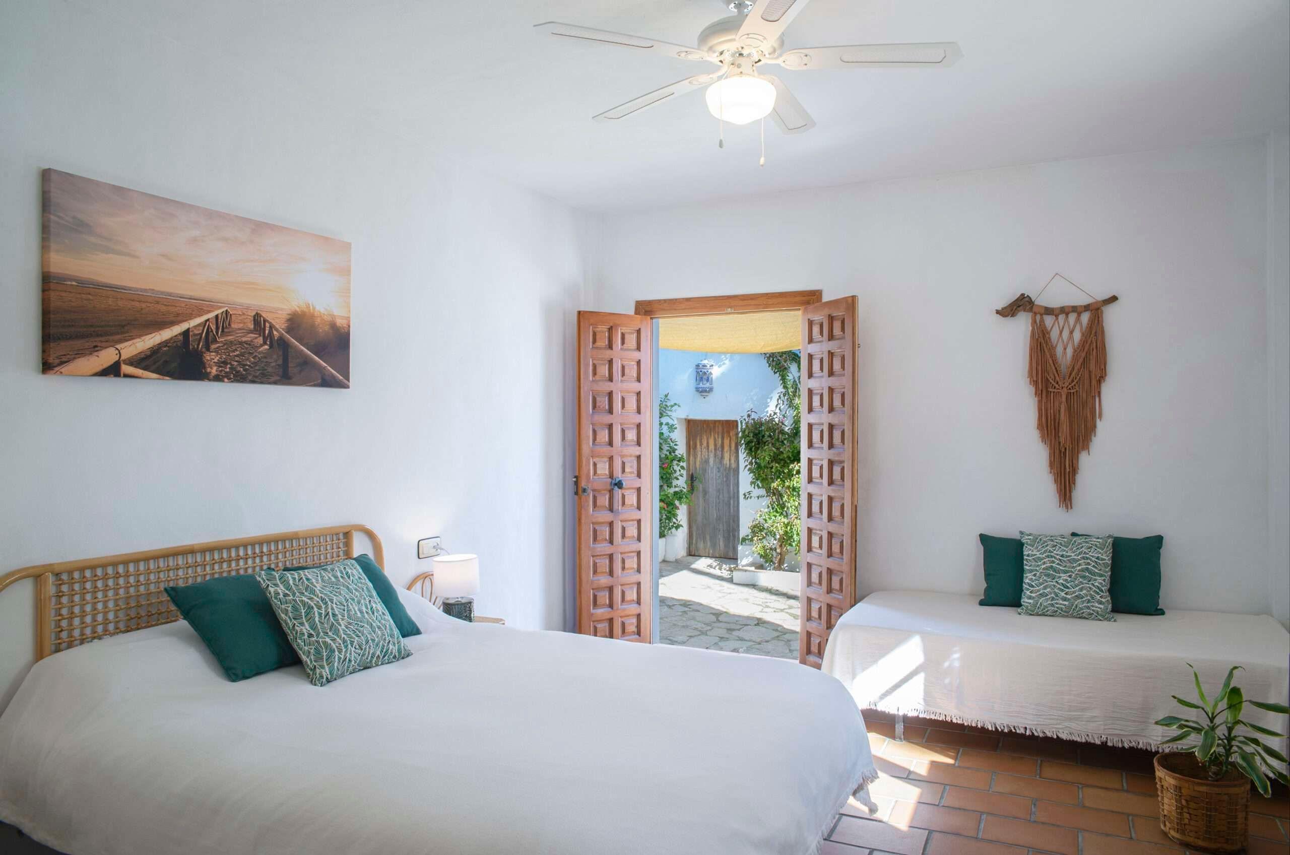 room with a big bed and a small bed, doors open to a terrace