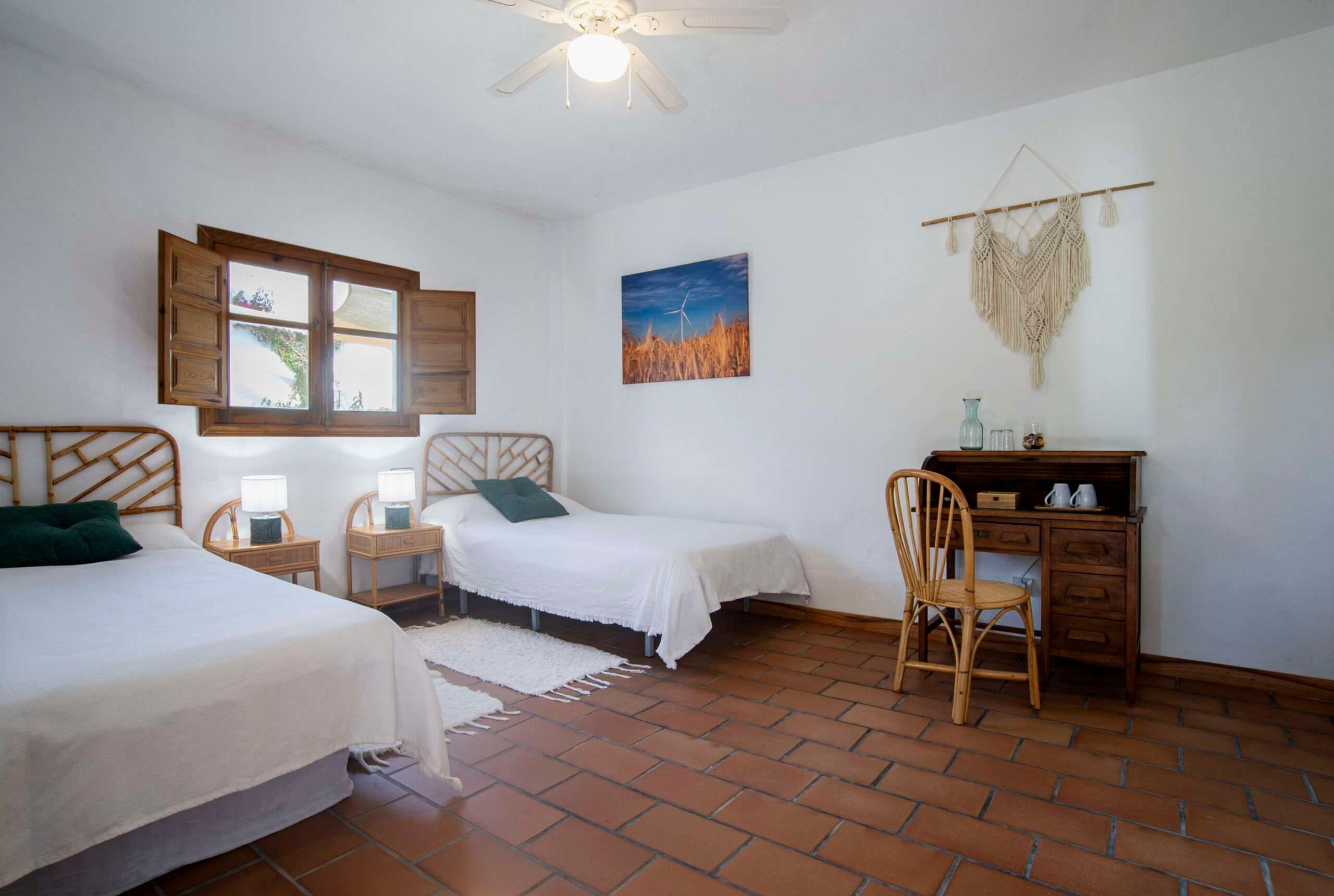 room with 2 single beds, a window in the middle and an atique desk