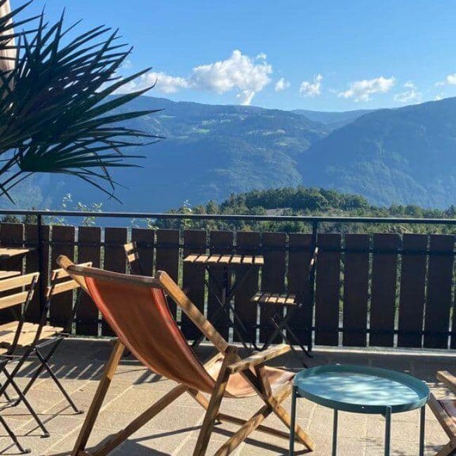 Terrace with deck chairs and a small table overlooking the mountain valley on a sunny day