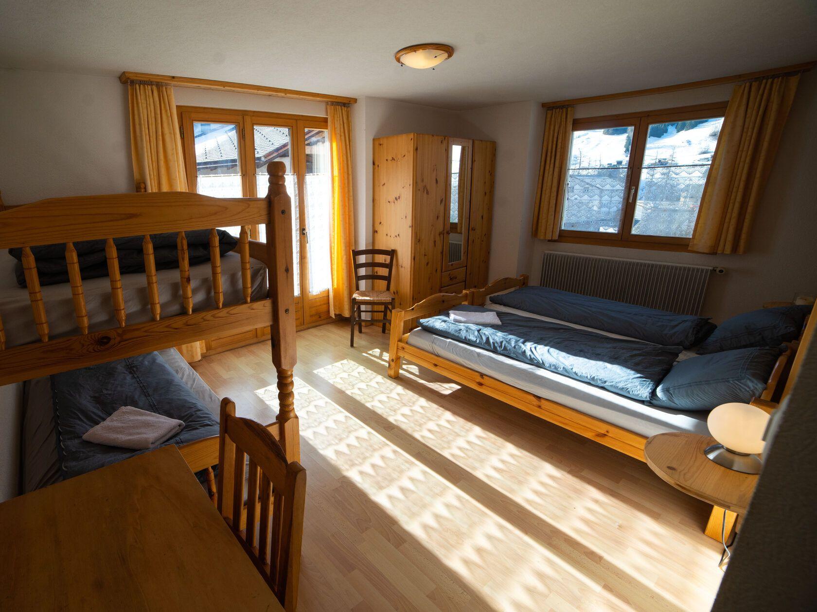 Shared room with bunk beds and additional beds, wooden furniture, and windows with mountain views