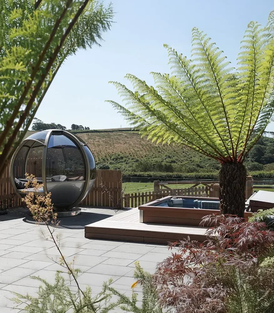 Outdoor tropical spa area with hot tub, tree ferns and countryside views