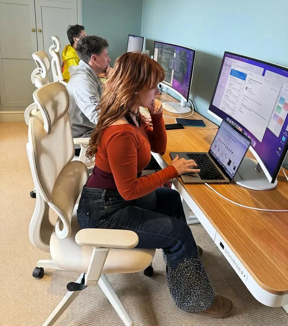 Froomies residents working at large 34" monitors in the co-working space with ergonomic chairs