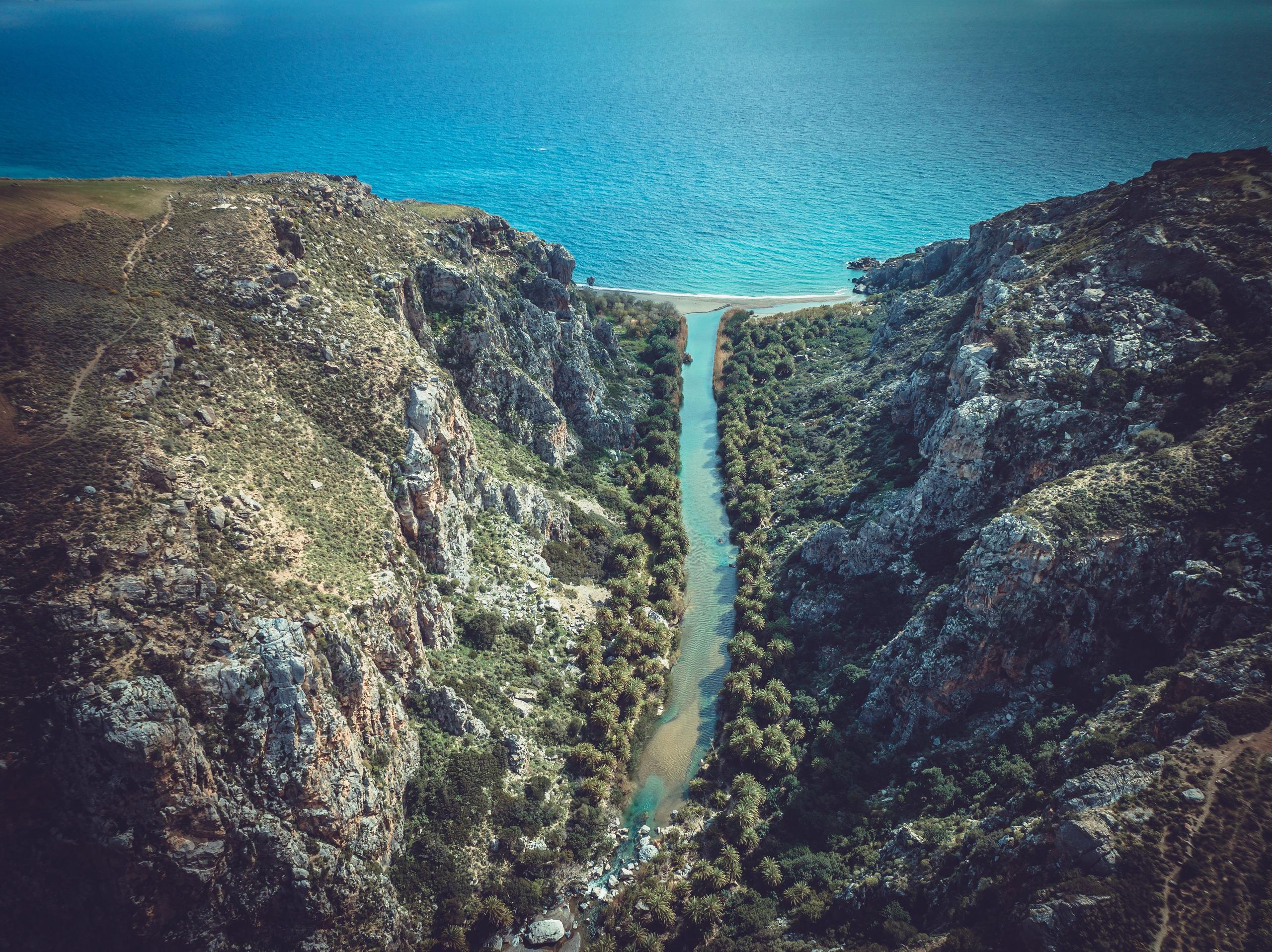 Rocky mountain landscape with green foliage, a river, and a beach. Rugged and serene.