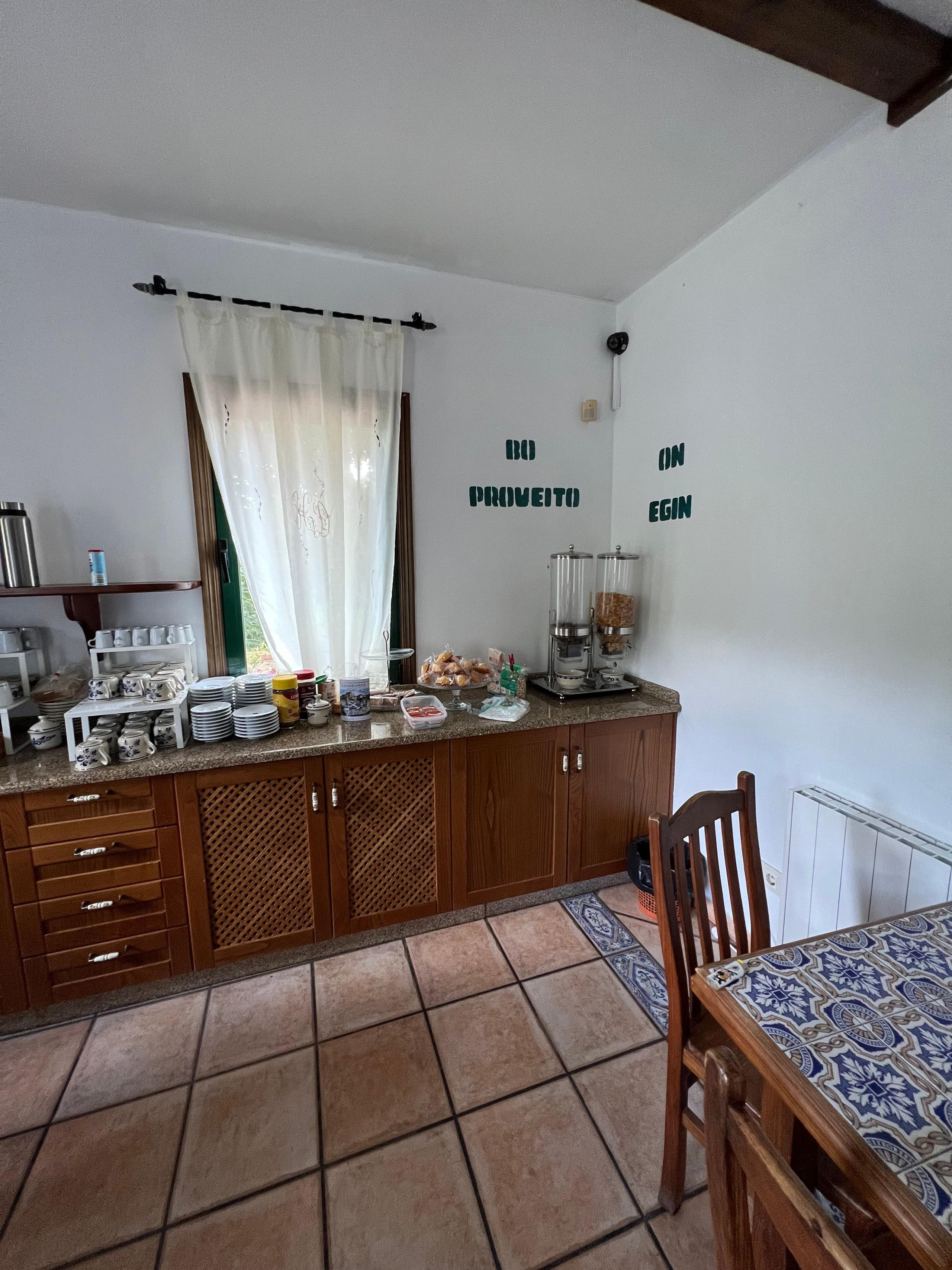 Shared kitchen breakfast corner with cereals, coffee machine and supplies, with a sign on the wall