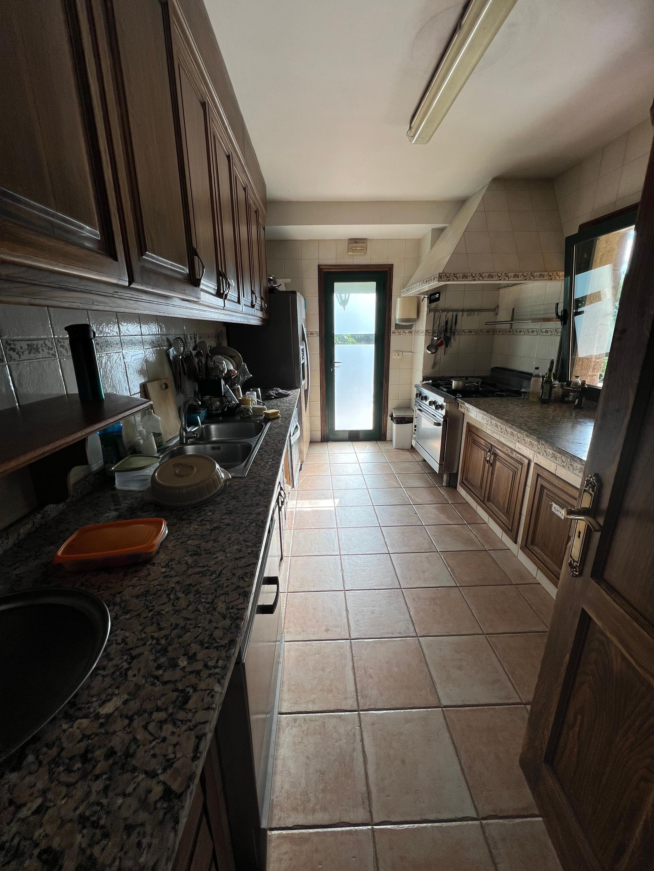 Interior view of the shared kitchen with wooden cabinets, tiled walls and cooking equipment