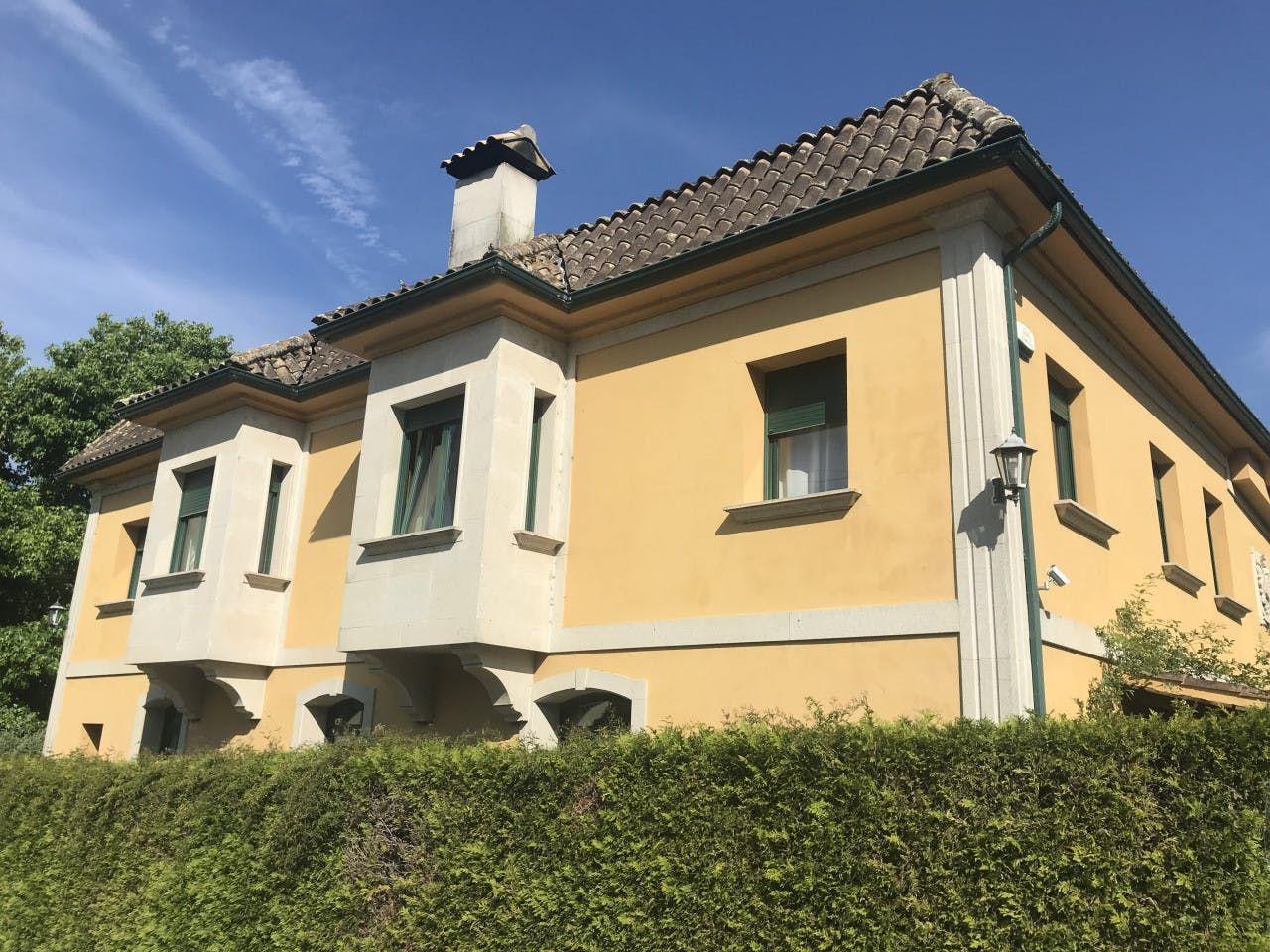 Exterior view of the coliving building showing the yellow facade and tiled roof under a blue sky
