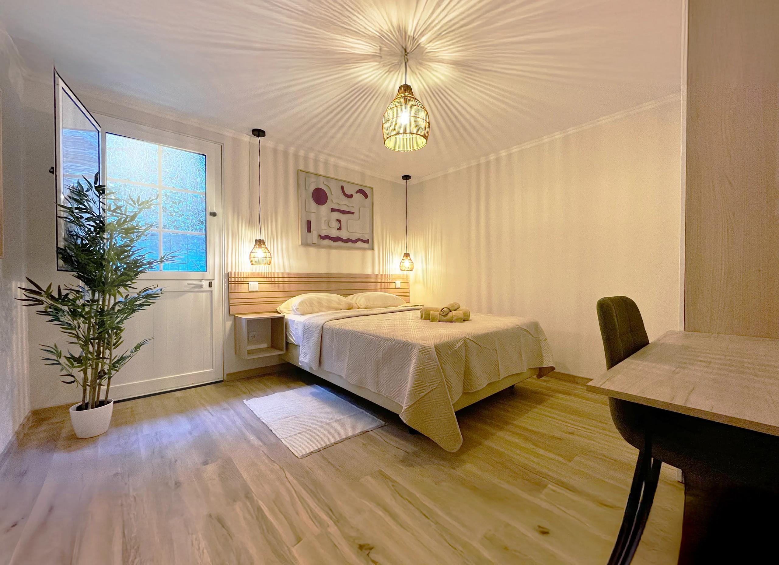 Double room with double bed, pendant lights, desk and direct outdoor access