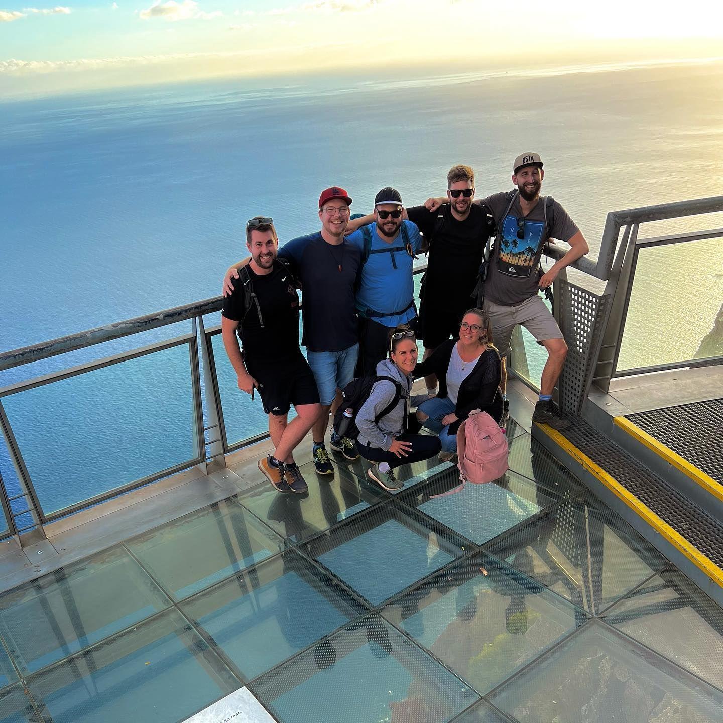 A large group of Homeoffice Madeira guests gather at Cabo Girao, Europe's highest sea cliff, soaking in the stunning panorama and sharing the unique experience of living and working on the picturesque island of Madeira.