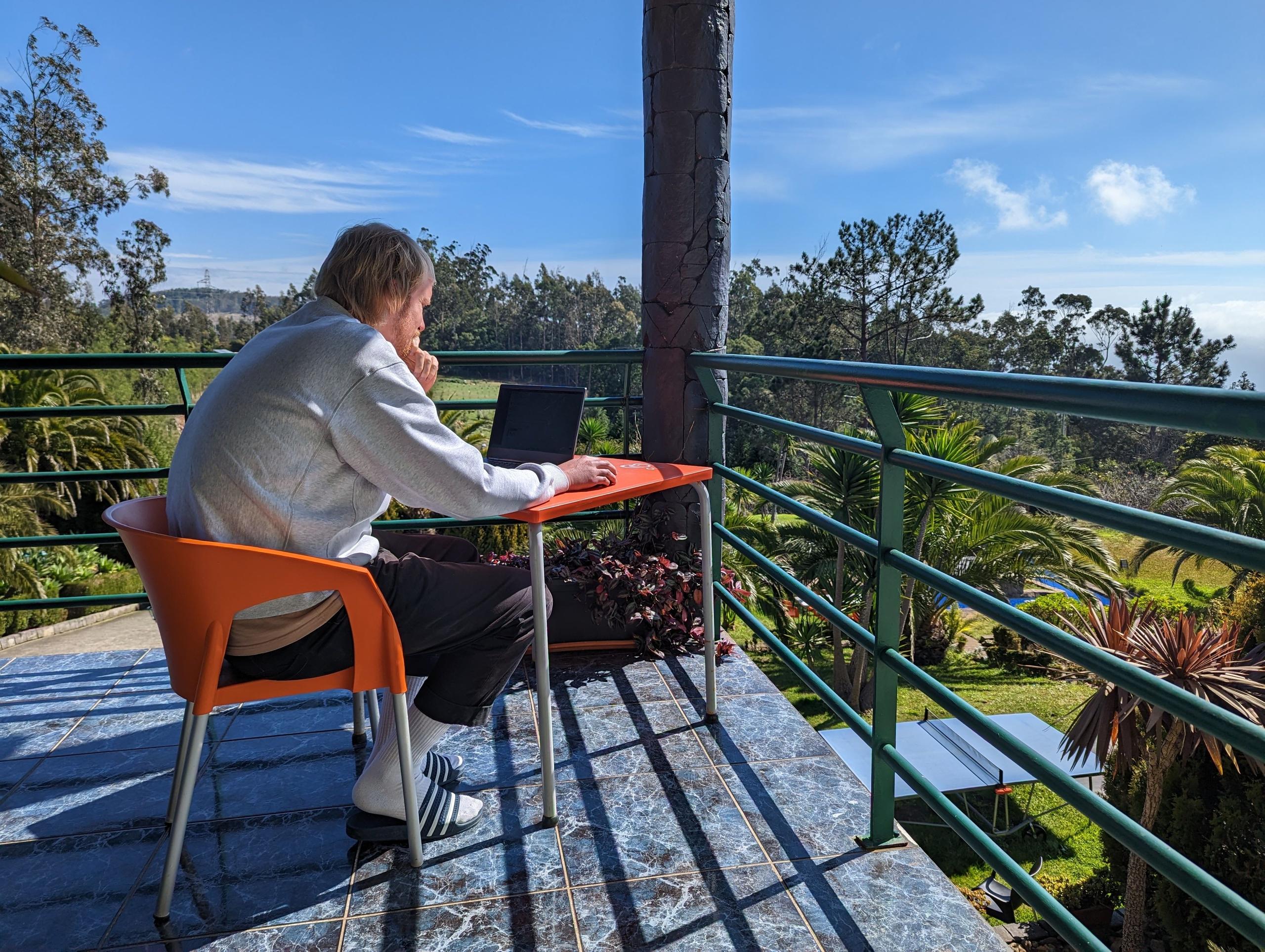 Soak up the amazing atmosphere as Paul enjoys working on the sunlit terrace of Homeoffice Madeira, where the blend of fresh air and stunning views fuels creativity and focus.
