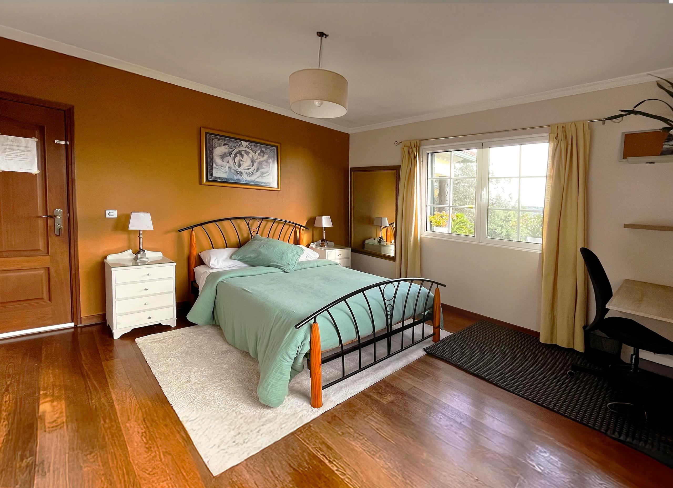 Double room with warm orange walls, double bed and desk in Room 09 Novelo