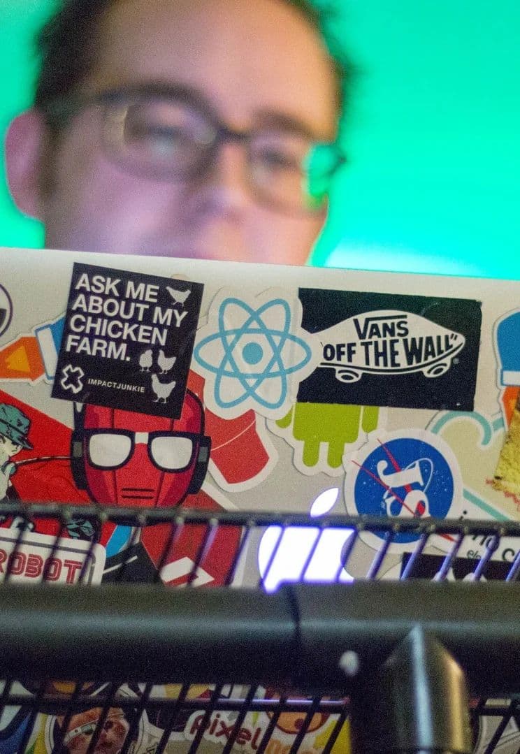 Person working on a laptop with stickers at Hub53 during a colearning session