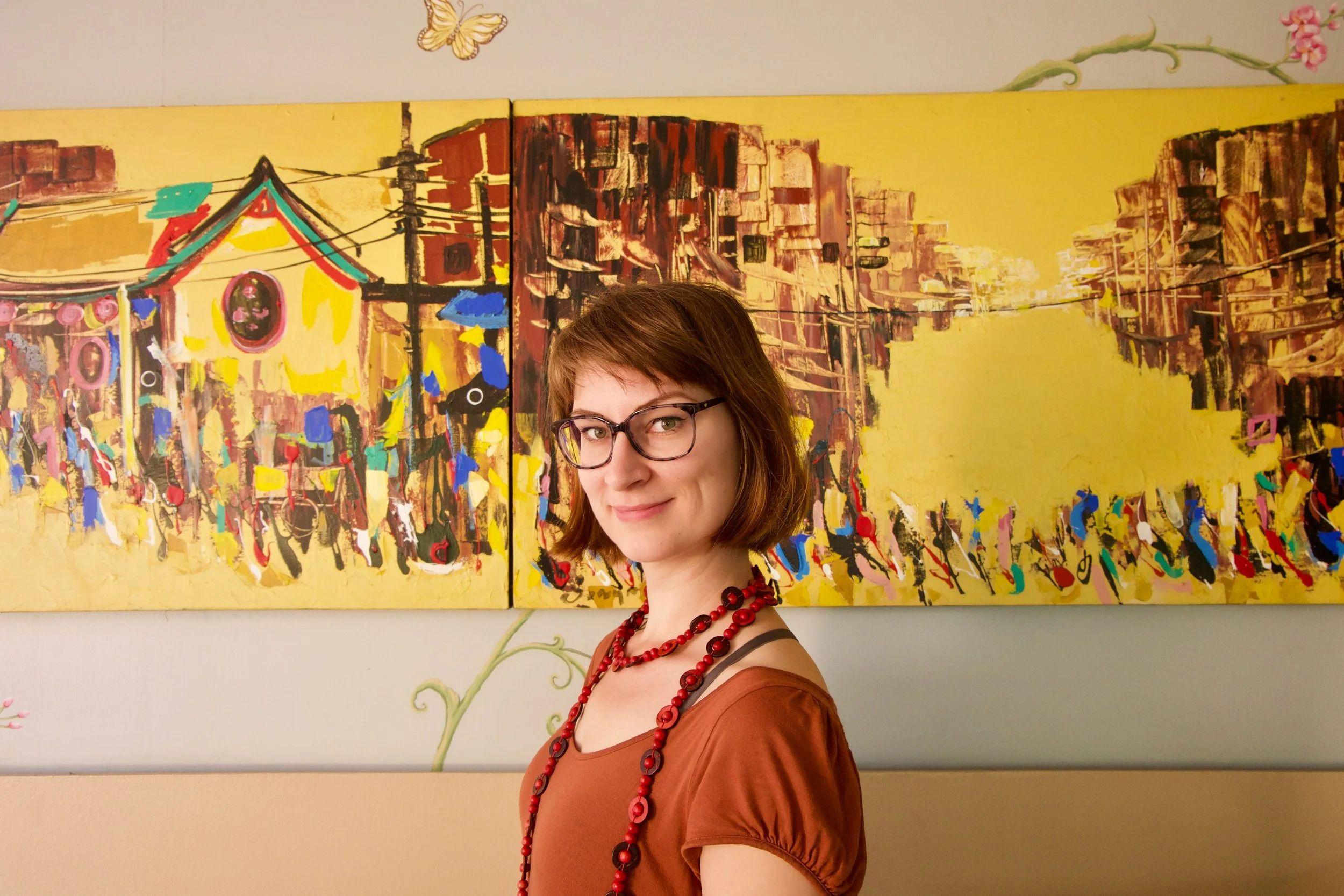 Hub53 resident standing in front of a colorful painting in the common area