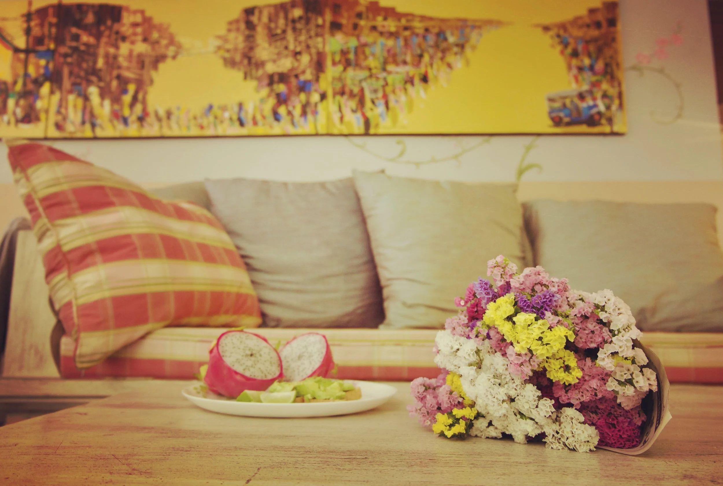 Sofa with colorful cushions, flowers and dragon fruit on a coffee table in the common living area