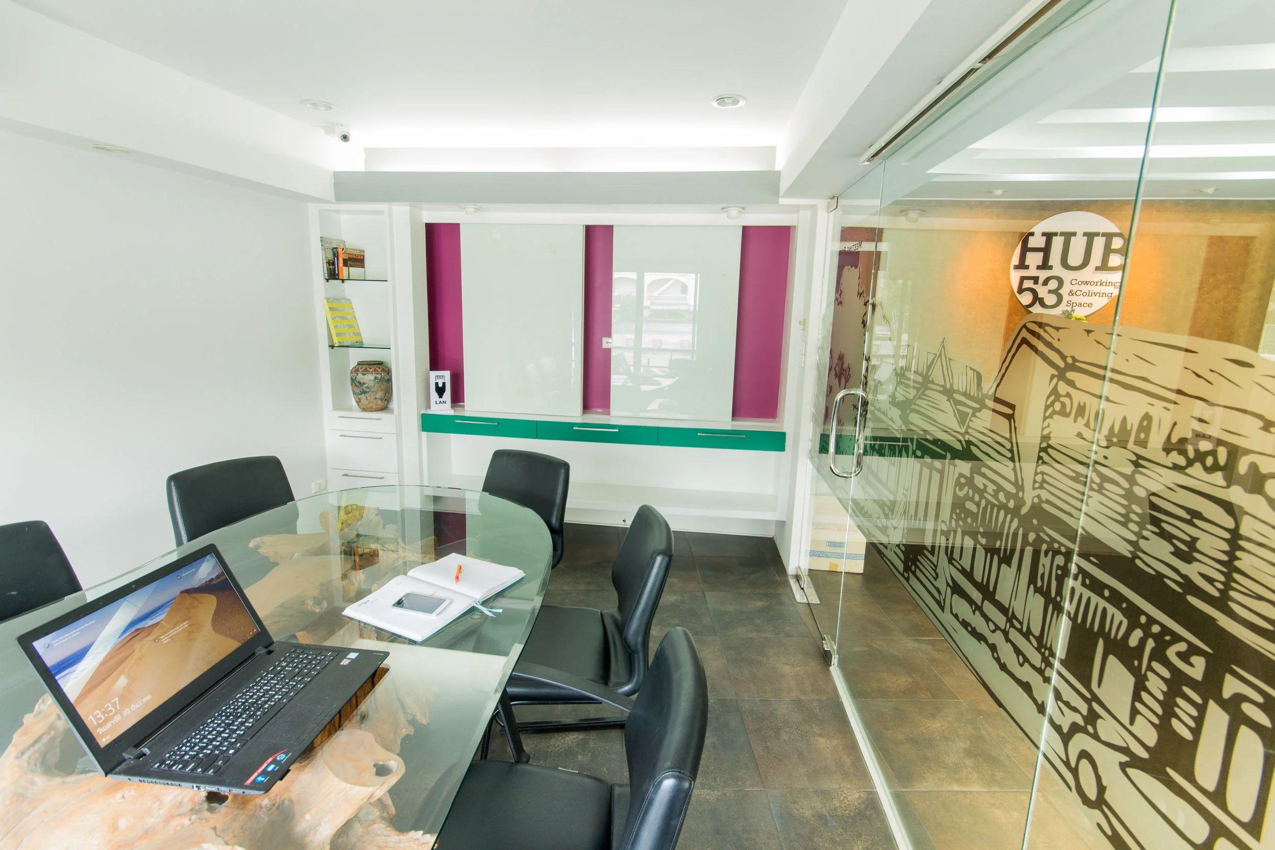 Large private office with glass table, black chairs and Hub53 branded glass partition