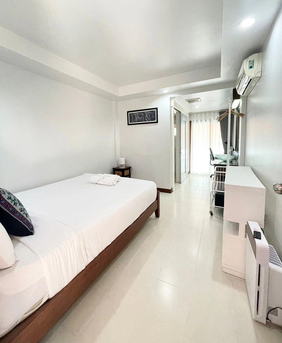 Modern Plus room with queen bed, white walls, desk, air purifier and balcony access