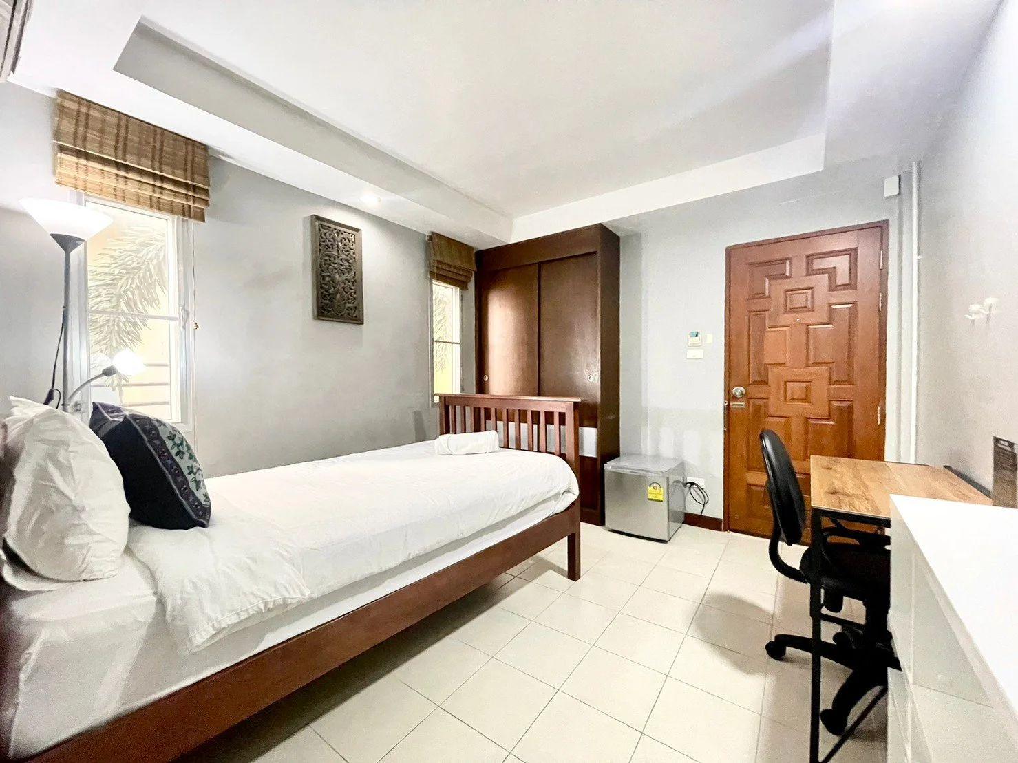 Superior room with twin bed, wooden wardrobe, desk, fridge and natural light from window