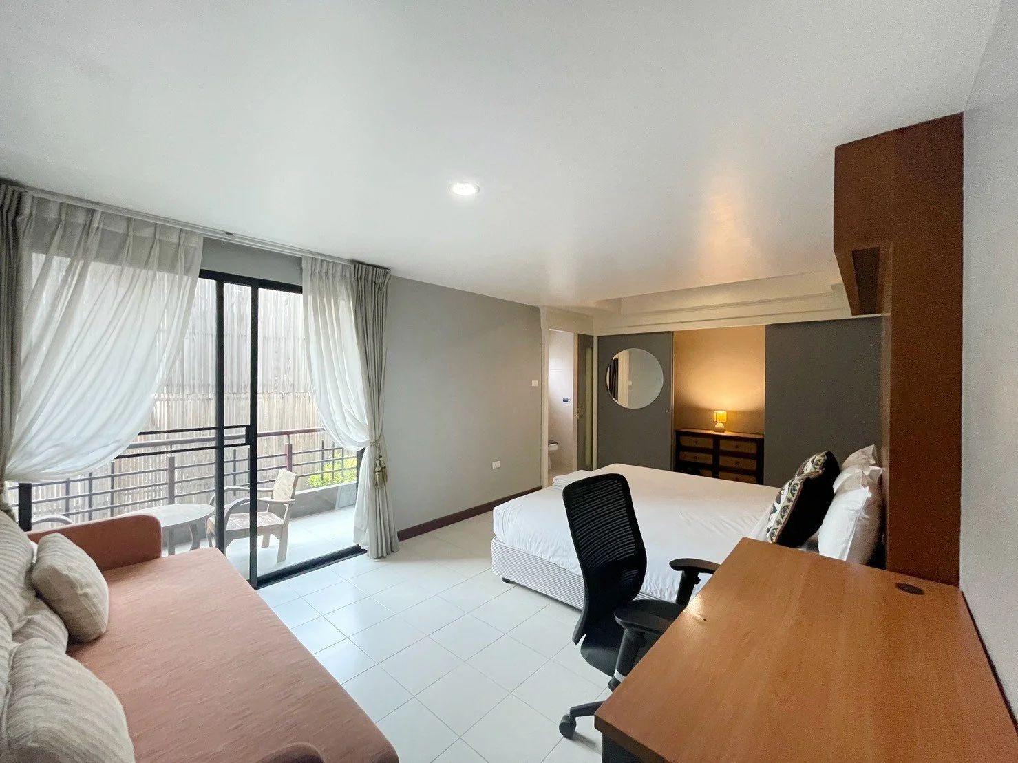 King room with king-sized bed, sofa, large balcony with sliding glass doors, desk and chair
