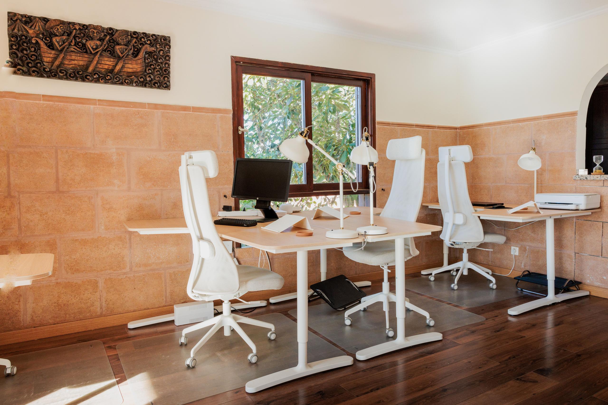 Close-up view of the coworking area with white desks, ergonomic chairs, and desk lamps