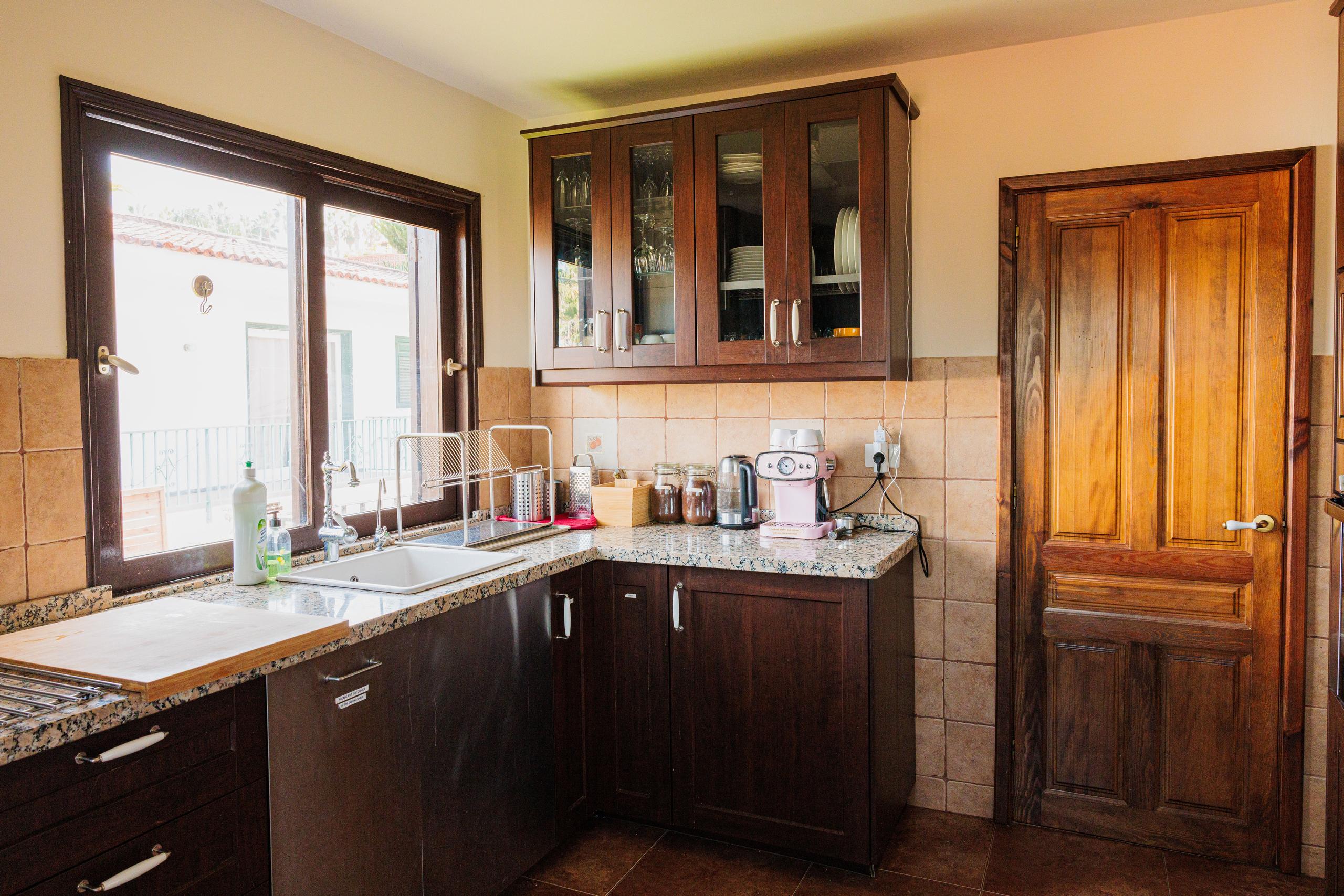 Fully equipped shared kitchen with dark wood cabinets, granite countertops, sink, and appliances