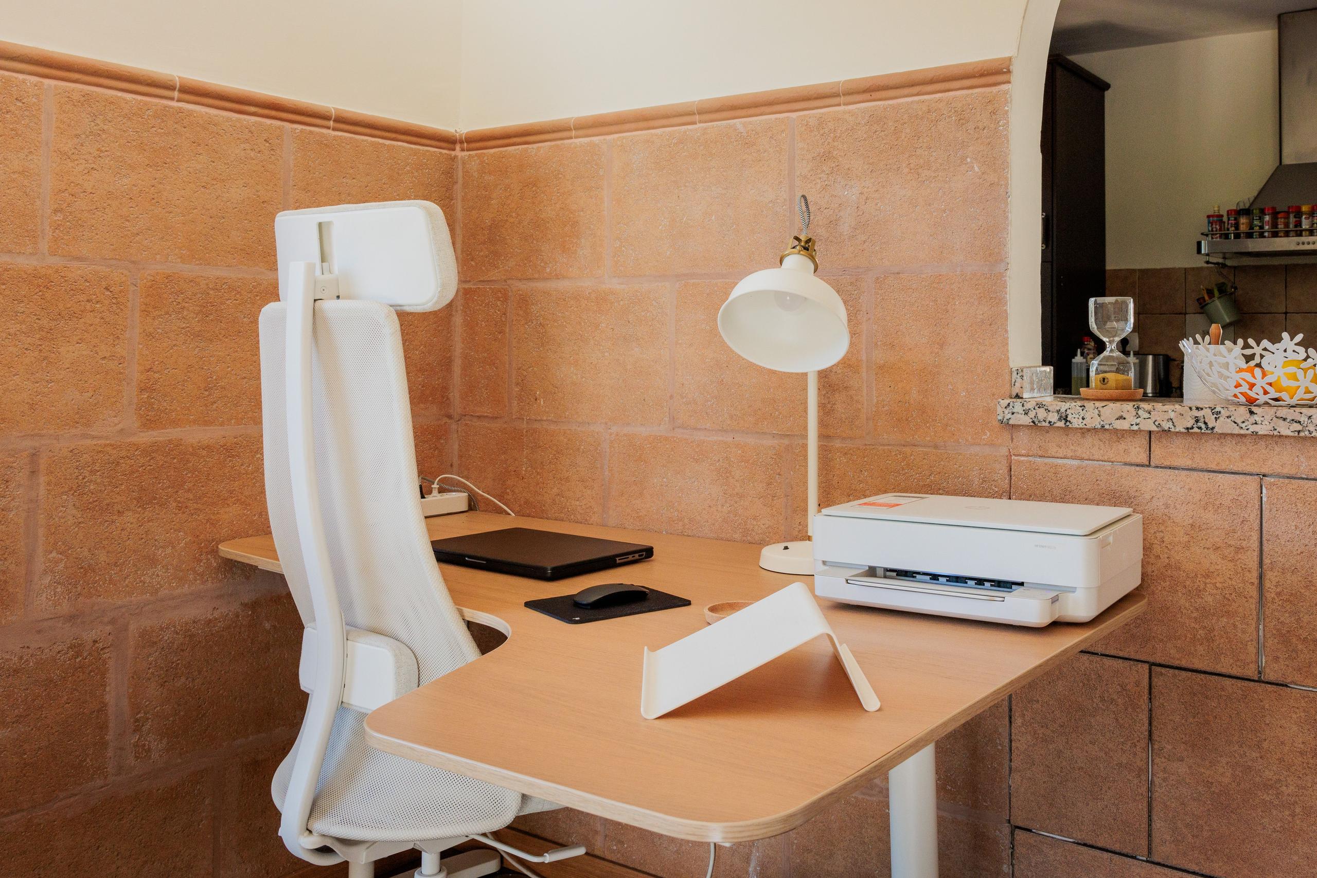 Individual coworking desk station with ergonomic chair, desk lamp, and printer
