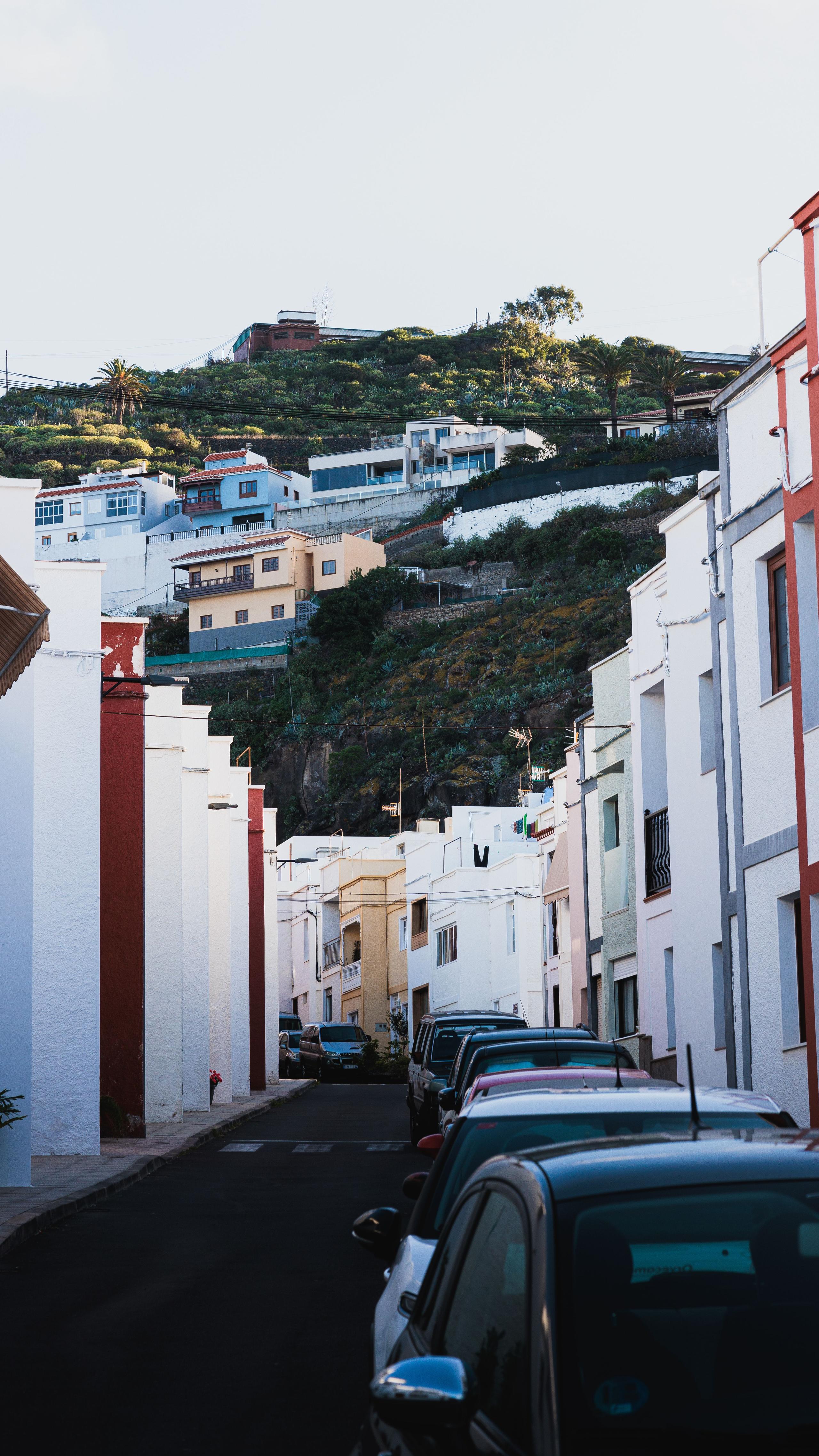 Narrow street in a Tenerife town with white buildings and parked cars