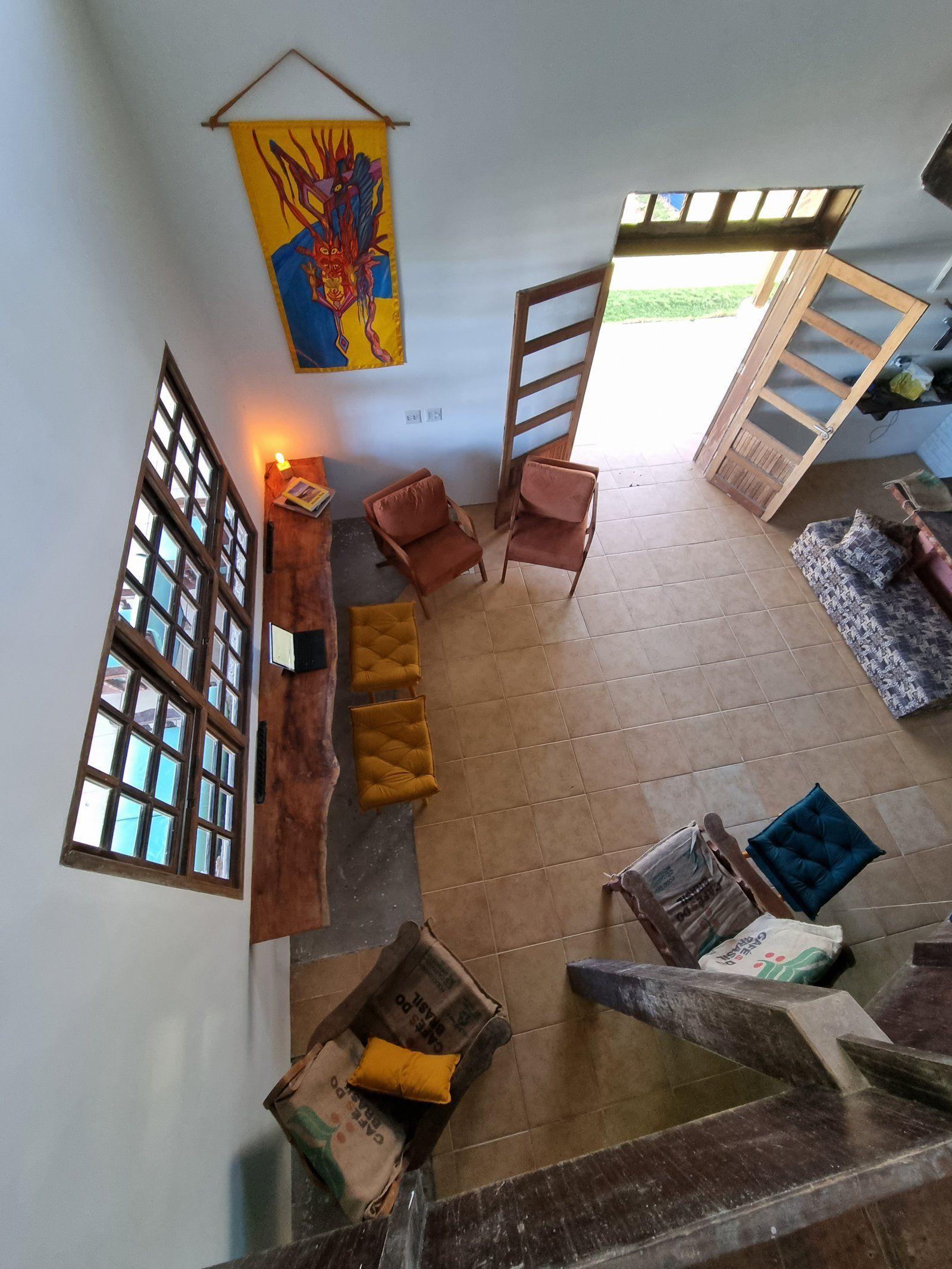 Aerial/overhead view of the communal living lounge with armchairs, a wooden bench, and decorative artwork on the wall.
