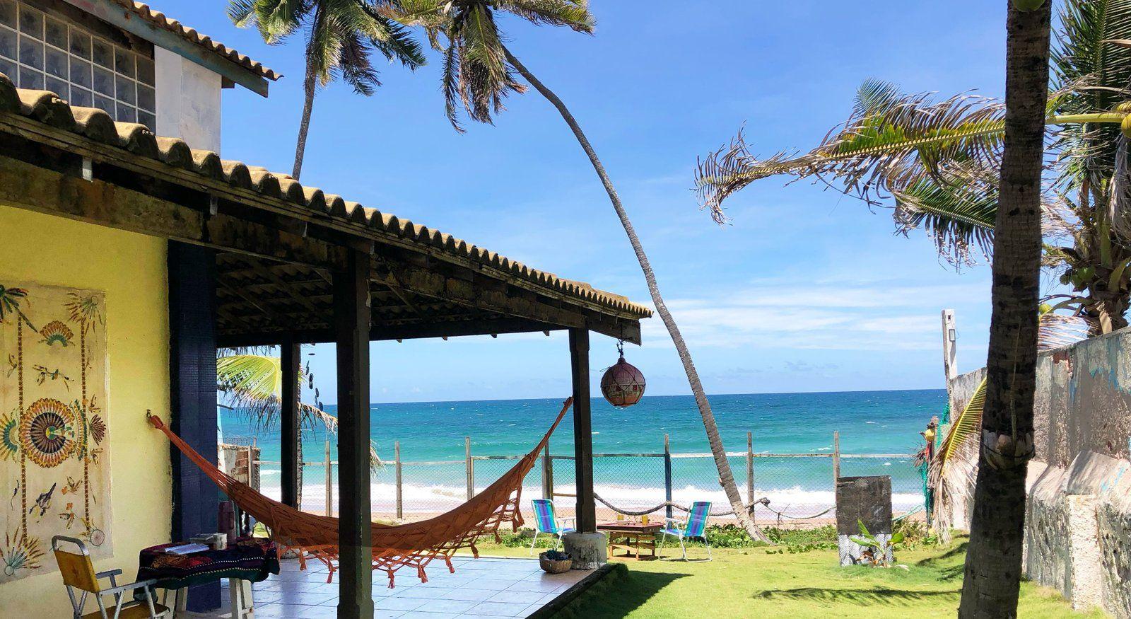 Covered terrace of the coliving with a hammock, chairs, and a direct view of the beach and ocean.