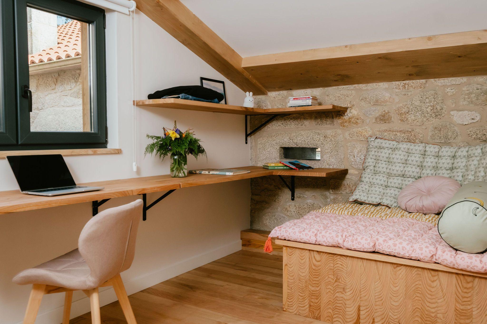 Small upstairs meeting and coworking room with wooden desk, laptop, shelves, and a cosy seating area