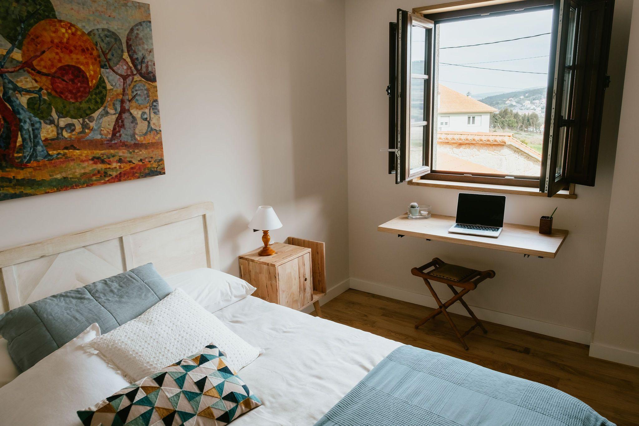 Double room A do Medio with double bed, colourful wall art, desk with laptop by the window overlooking the surroundings