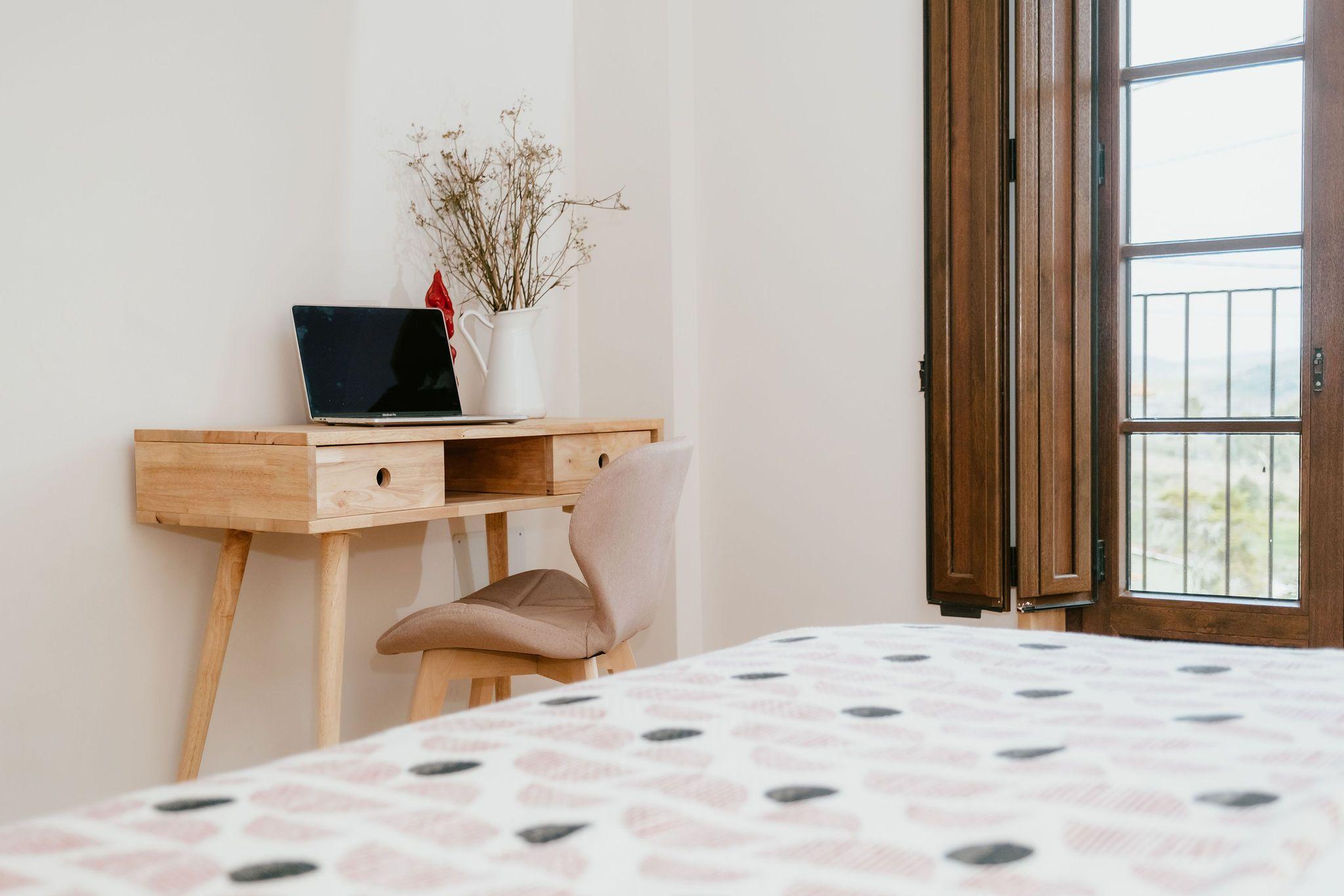 Premium double room O Avó showing the wooden desk with laptop and balcony doors with garden view