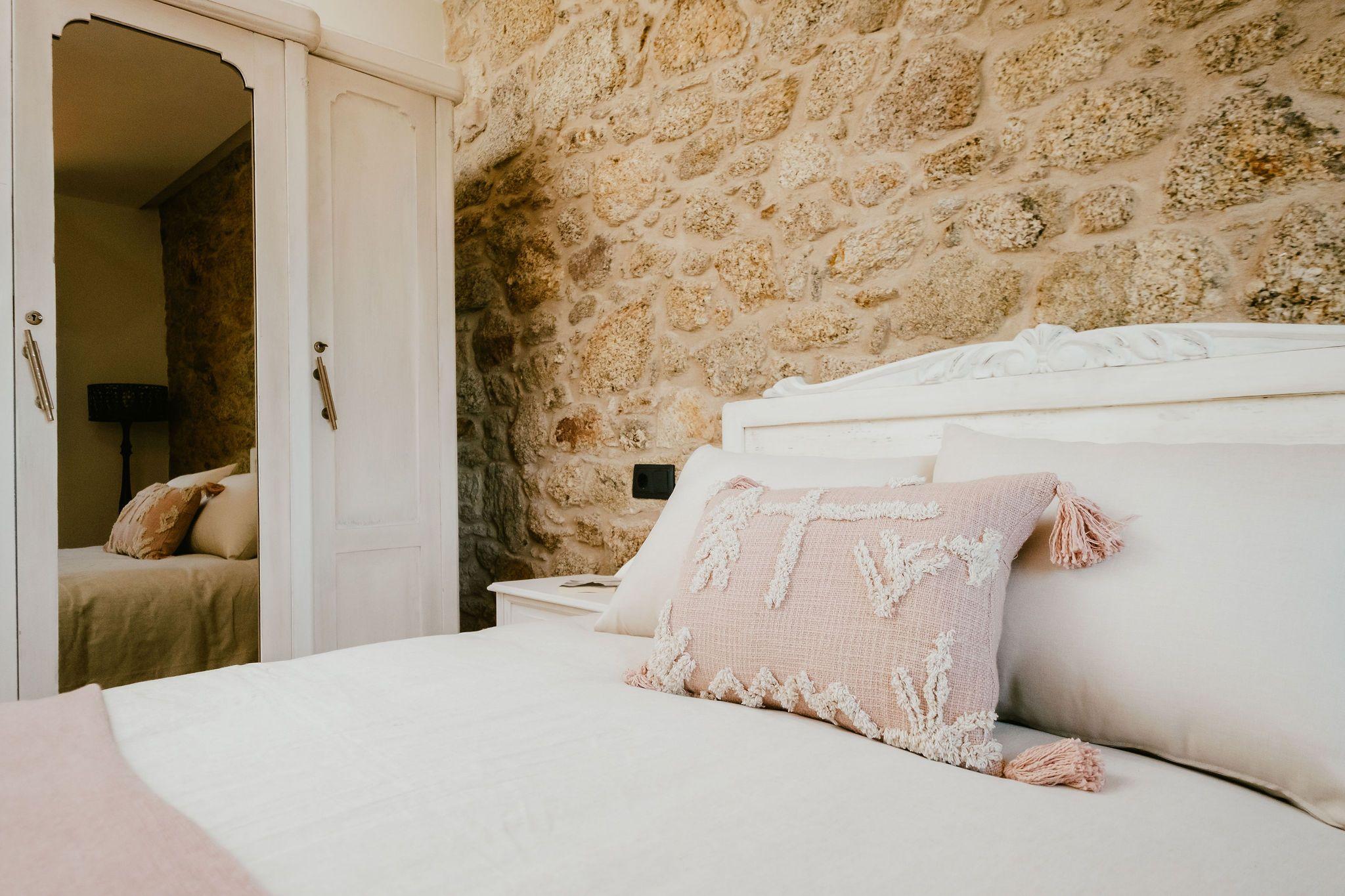 Double room As Vacas with white bed, stone wall, and view into private bathroom