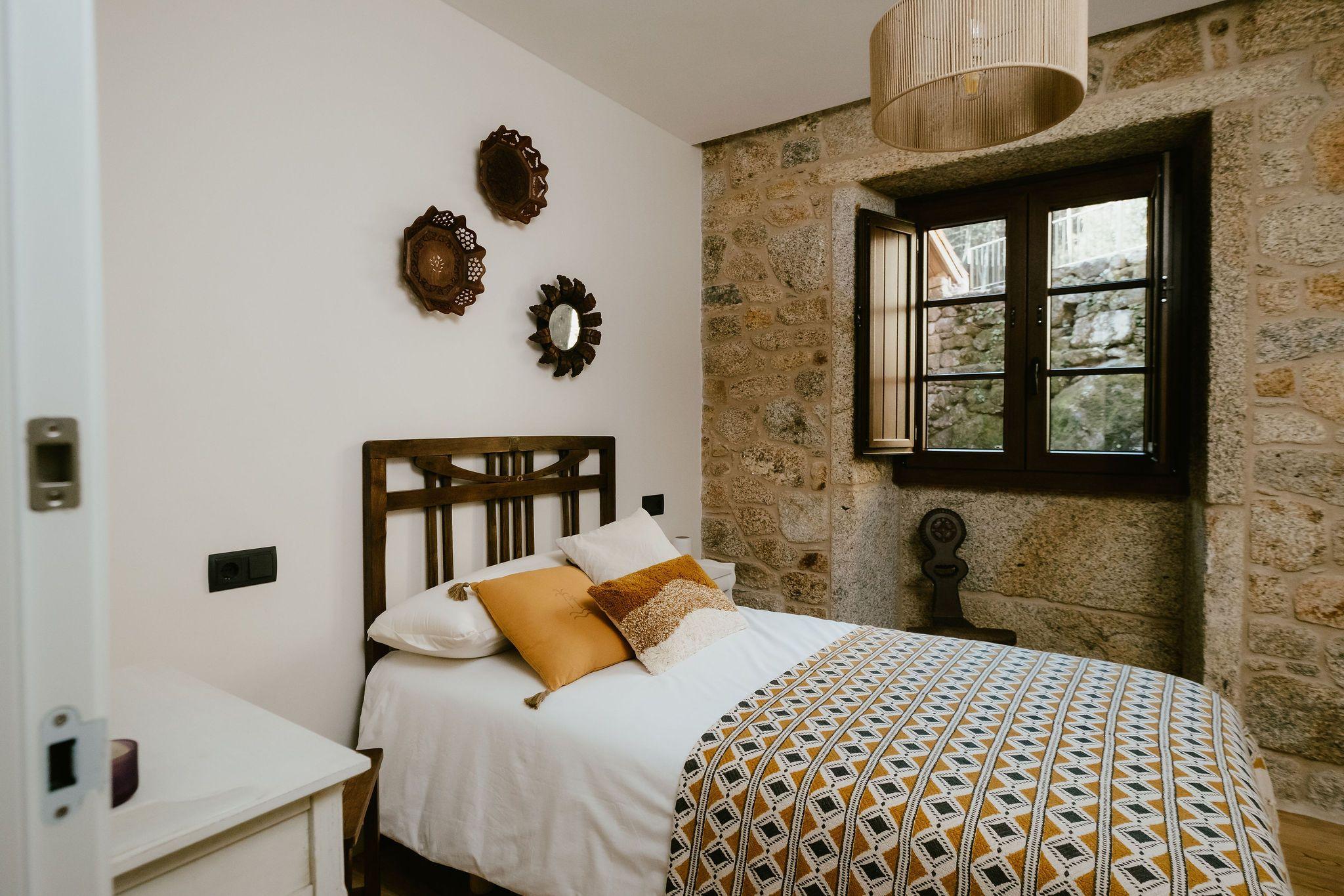Single room A Eira with bed, stone wall, and window with traditional wooden shutters
