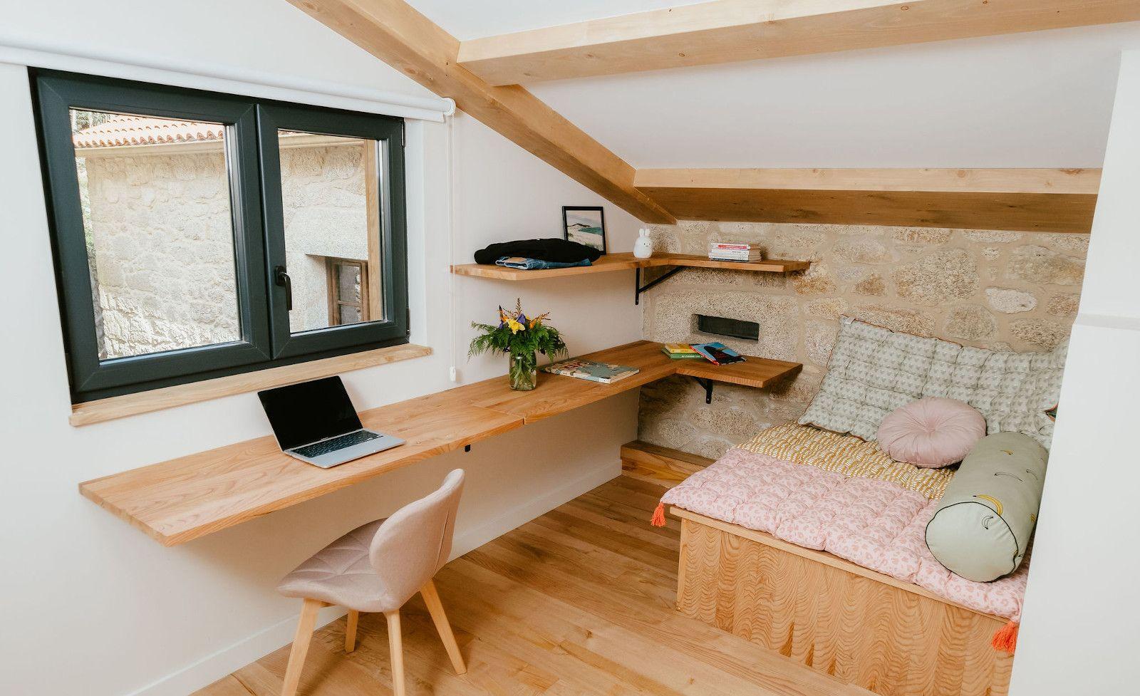 Small upstairs meeting and call room with a long wooden desk, chair, shelves, and a cosy seating area