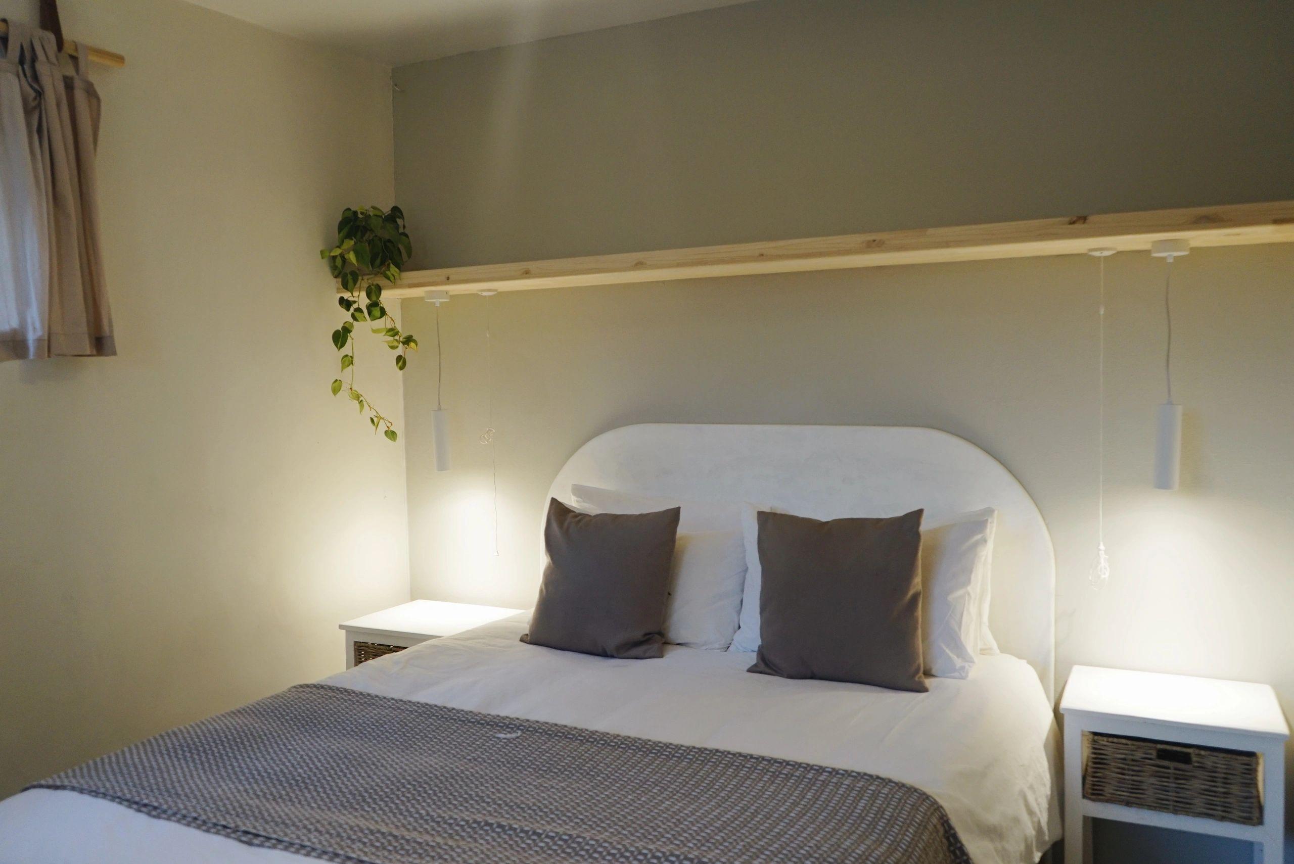 Cosy bedroom with a double bed, pendant lights, shelf with trailing plant, and bedside tables