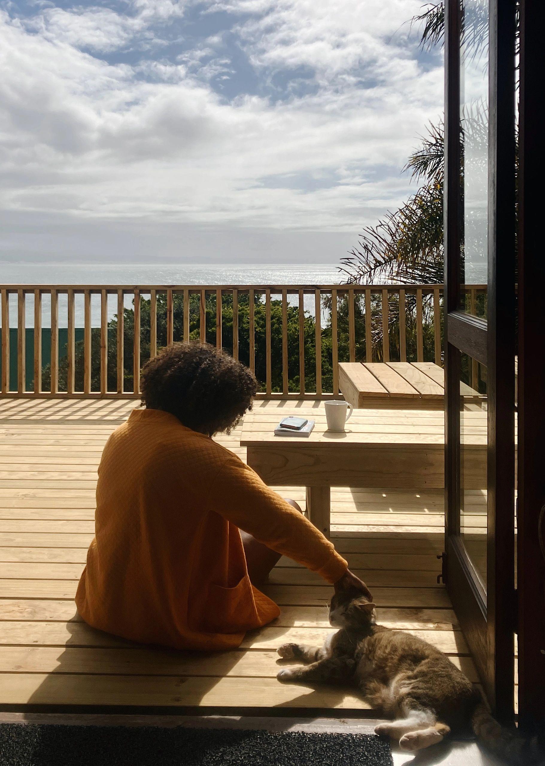 Resident sitting on the wooden sundeck with a cat, enjoying the ocean view