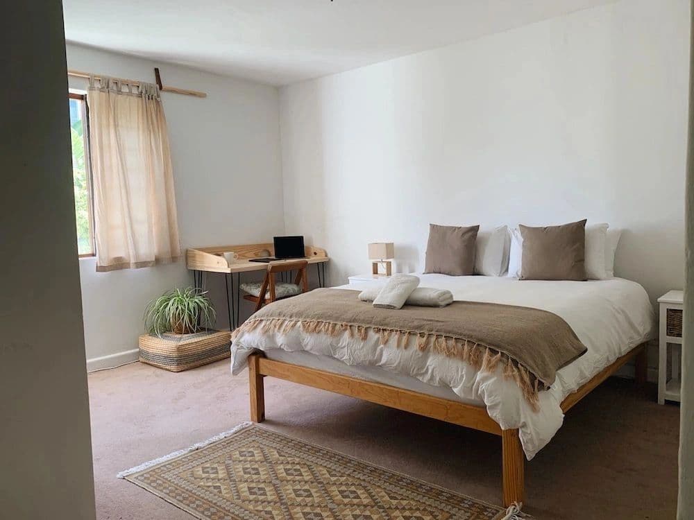 Spacious bedroom with a double bed, wooden desk, wardrobe, and garden-facing windows